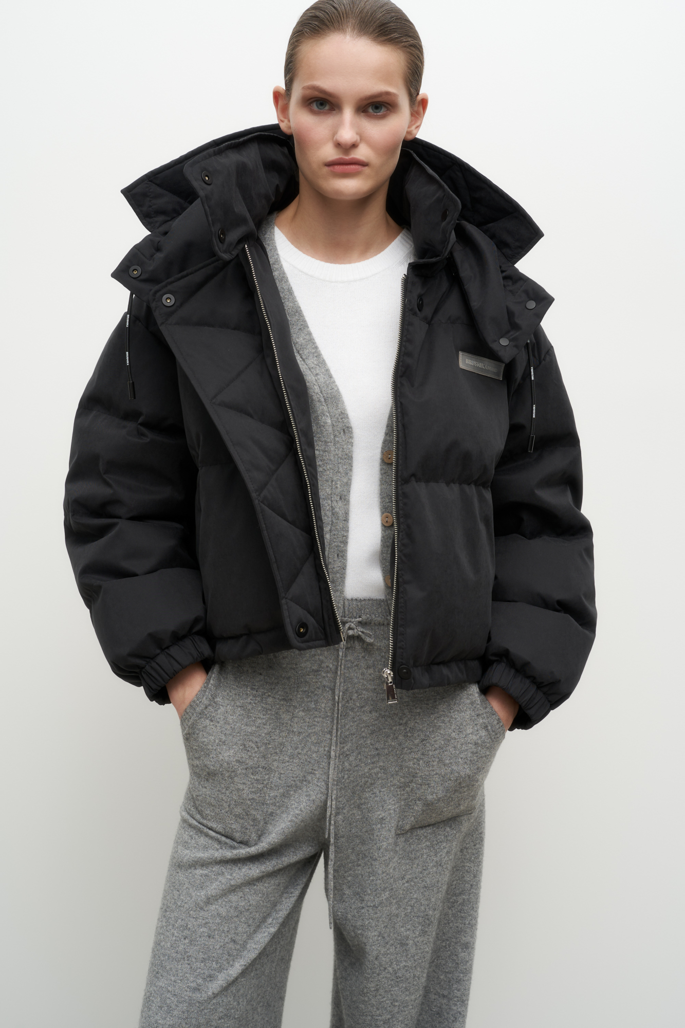 Утепленный пуховик с воротником-стойкой и капюшоном на молнии. Модель свободного силуэта с боковыми карманами, спущенным плечом и брендированным ярлыком на груди. Застежка на потайную молнию и кнопки. Наполнитель натуральный пух 90% перо 10%.