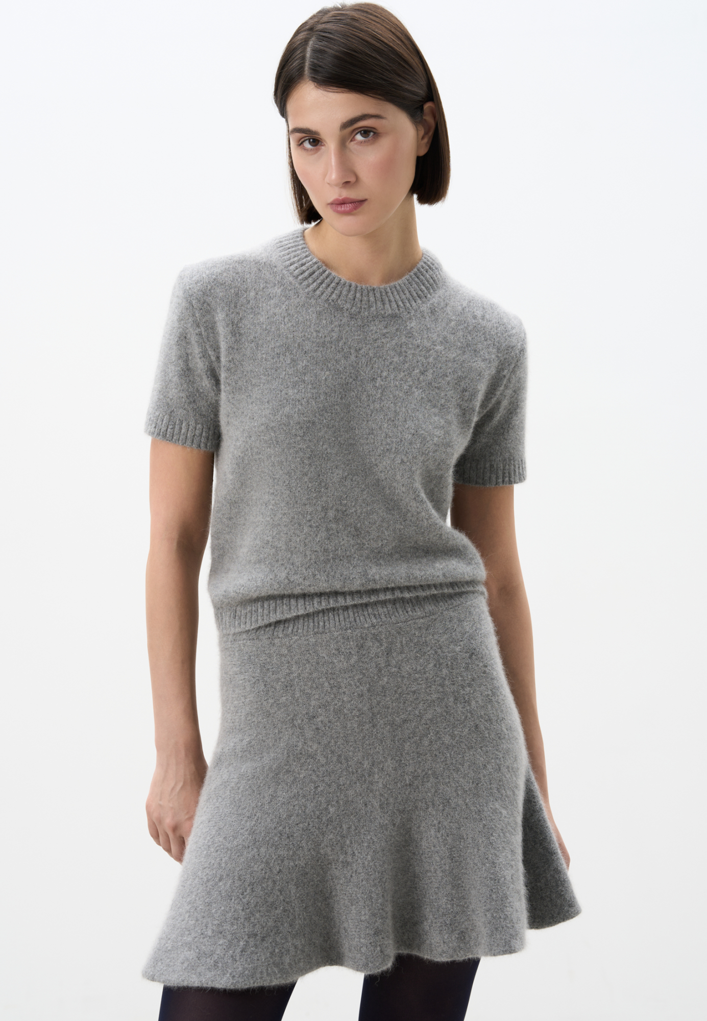 Трикотажная футболка из пуха лисы. Модель свободного силуэта, с коротким рукавом и круглым вырезом горловины. Края изделия выполнены в рубчик. Дополнить образ можно юбкой.