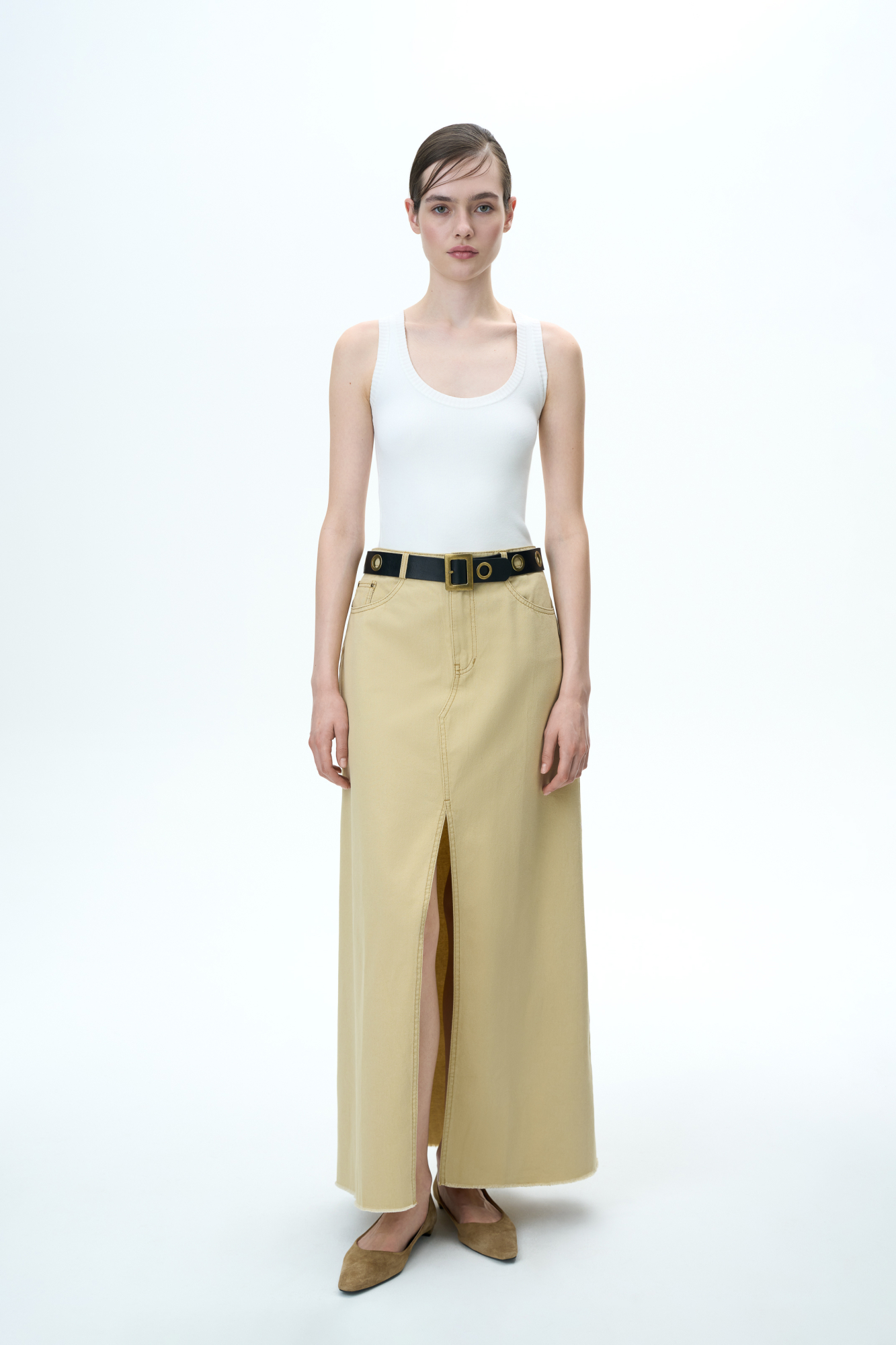 Джинсовая юбка длины макси из 100% хлопка. Модель со средней посадкой, с разрезом спереди и необработанным низом. Застежка на молнию и пуговицу.