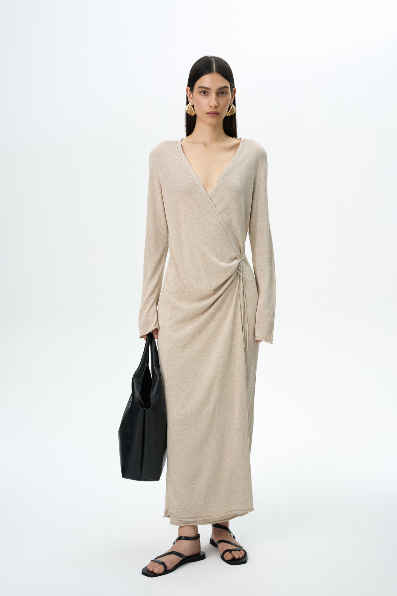 Трикотажное платье длины миди из тонкой вискозы. Модель приталенного силуэта на запах, с V-образным вырезом горловины, длинными расклешенными рукавами и кулиской на талии. 