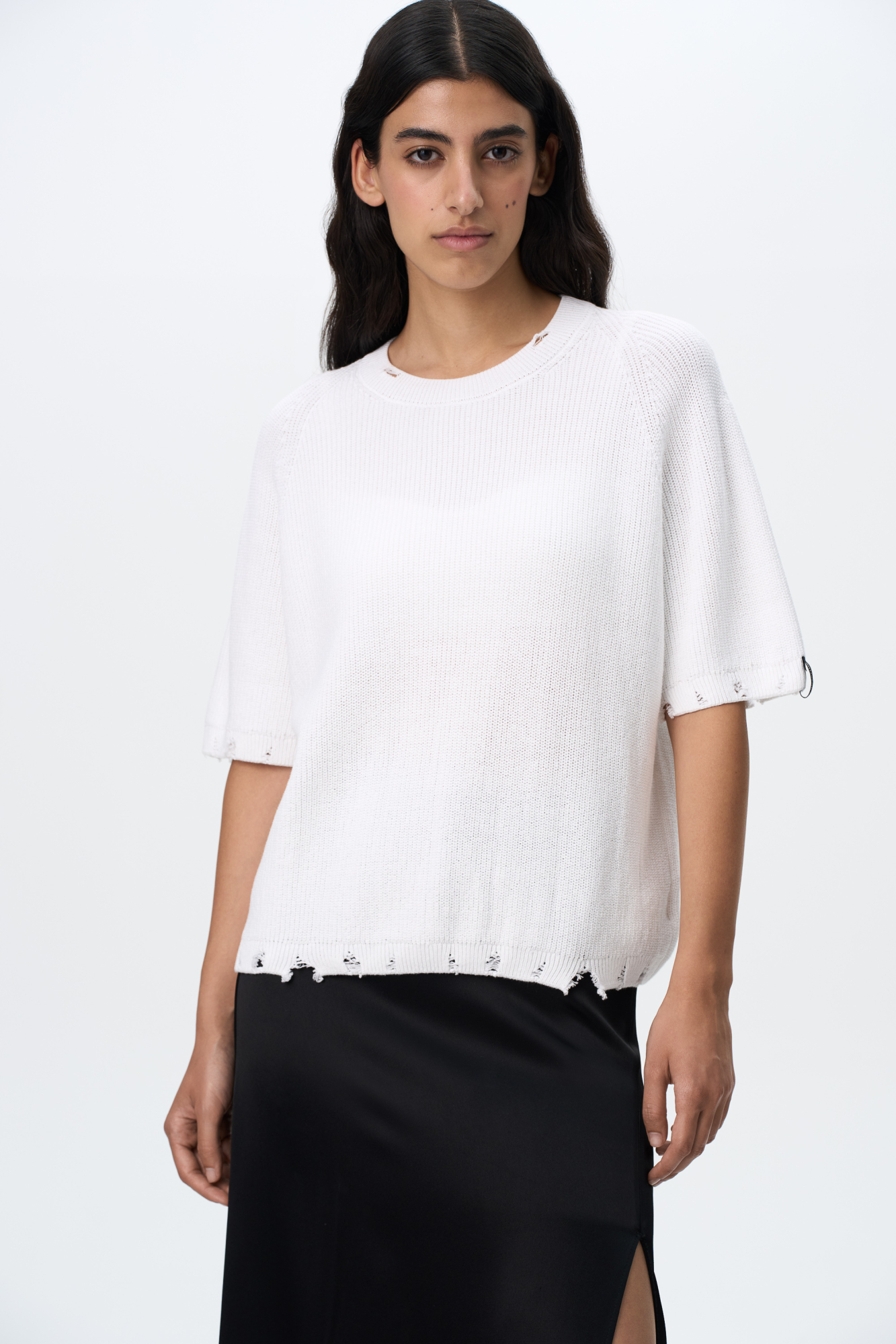 Трикотажная футболка из 100% хлопка. Модель свободного силуэта, со спущенной линией плеча, коротким рукавом и брендированным ярлыком на рукаве. Имитация необработанного края по низу изделия, на манжетах и воротнике. 