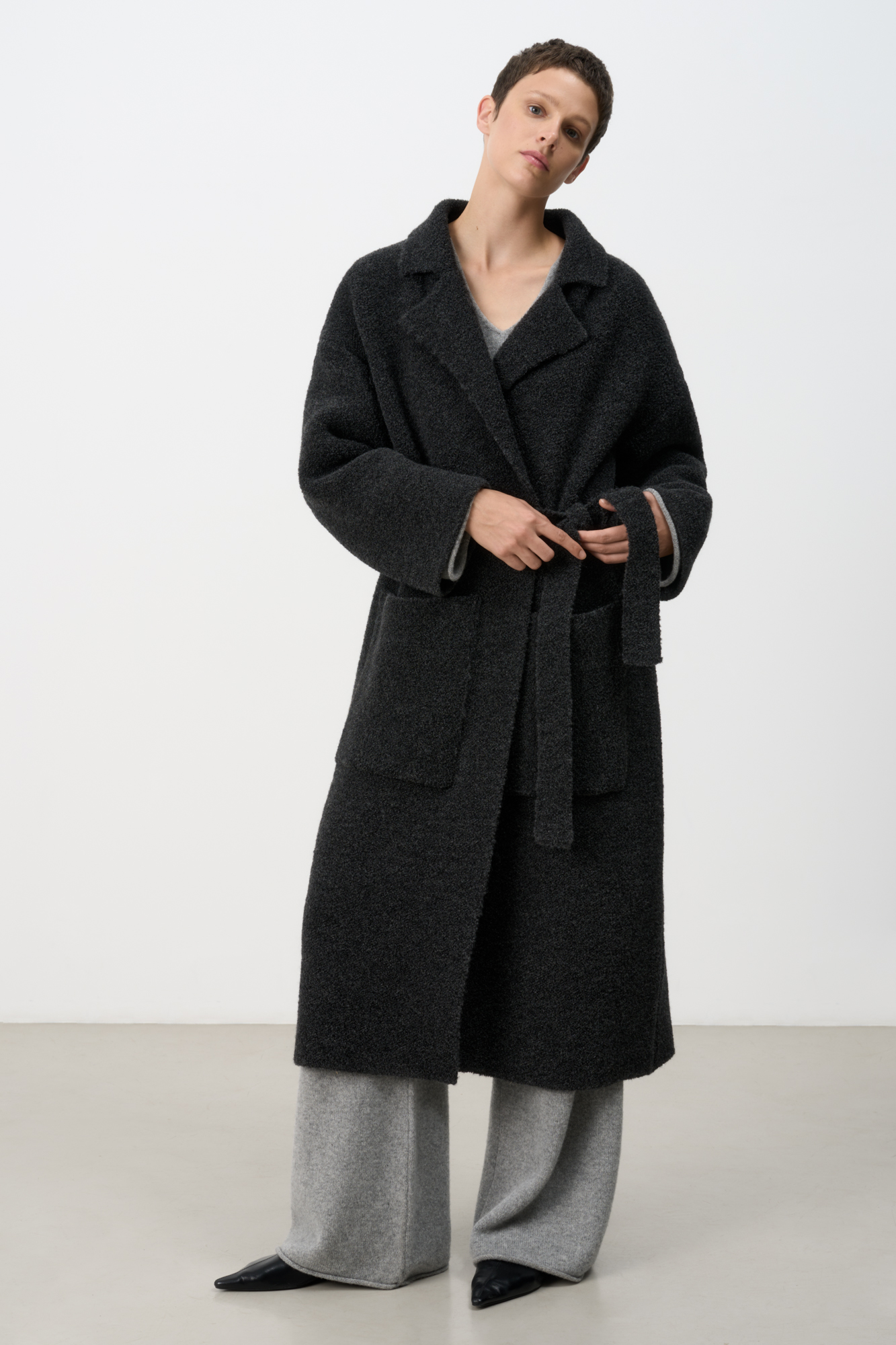 Трикотажное пальто на запах из смесовой шерсти с поясом в тон. Модель свободного силуэта со спущенной линией плеча и накладными карманами. Отложной воротник с прямоугольными лацканами. Изделие без подкладки. Дополнить образ можно шарфом и шапкой в тон.