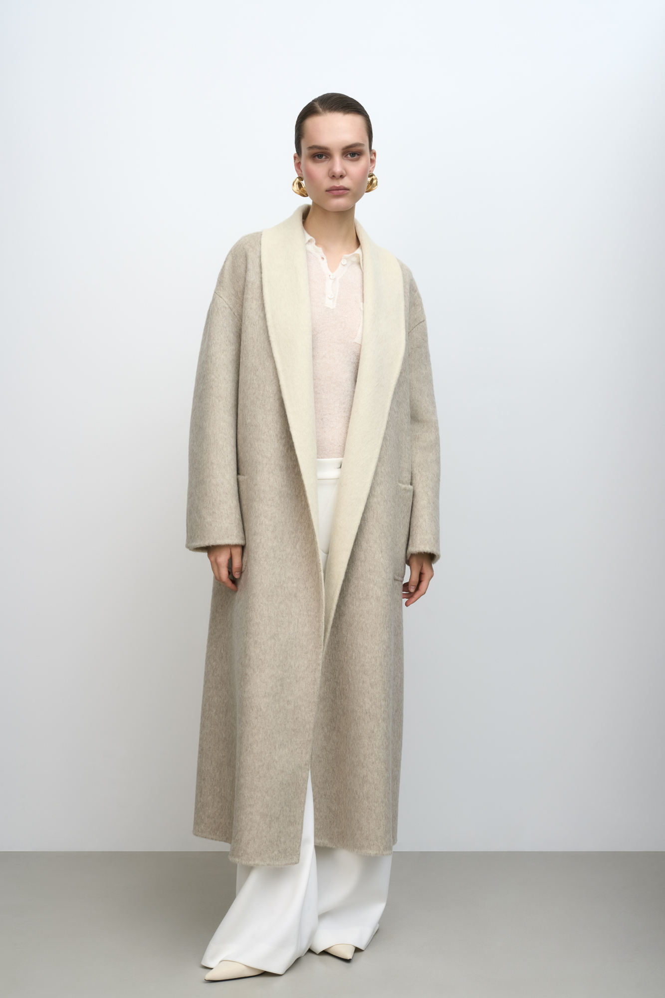 Пальто-халат из двусторонней ткани. В составе 80% шерсти с добавлением 10% ангоры и 10% шелка. Отложной воротник, накладные карманы и тонкий ремень в тон основной ткани. При пошиве этого изделия была использована технология double face, благодаря которой внутренняя сторона выглядит также аккуратно, как и внешняя.