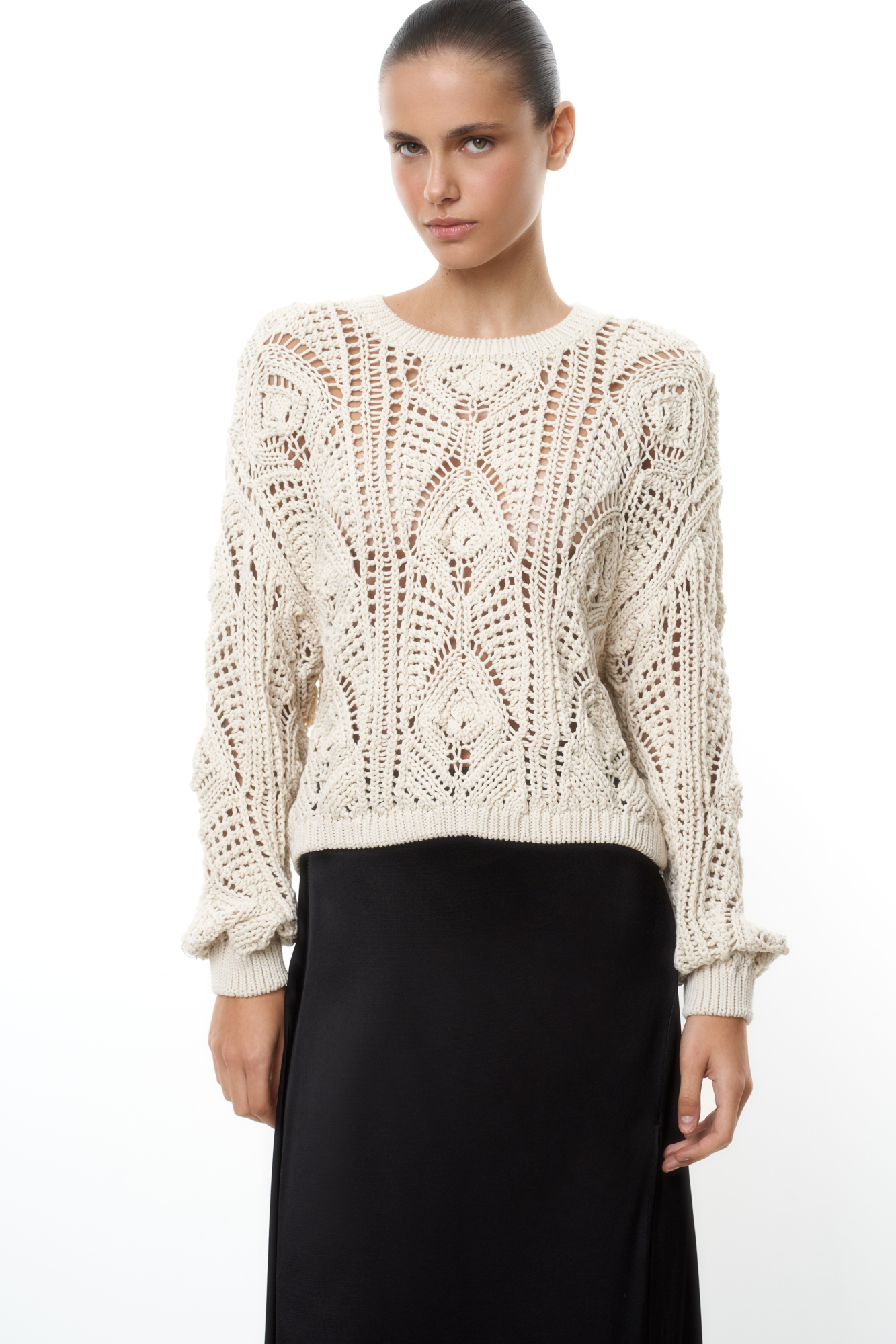 Трикотажный джемпер из хлопка, выполненный ажурной вязкой с орнаментом. Модель свободного силуэта с длинными рукавами и круглым вырезом горловины. Манжеты и низ изделия выполнены в рубчик.