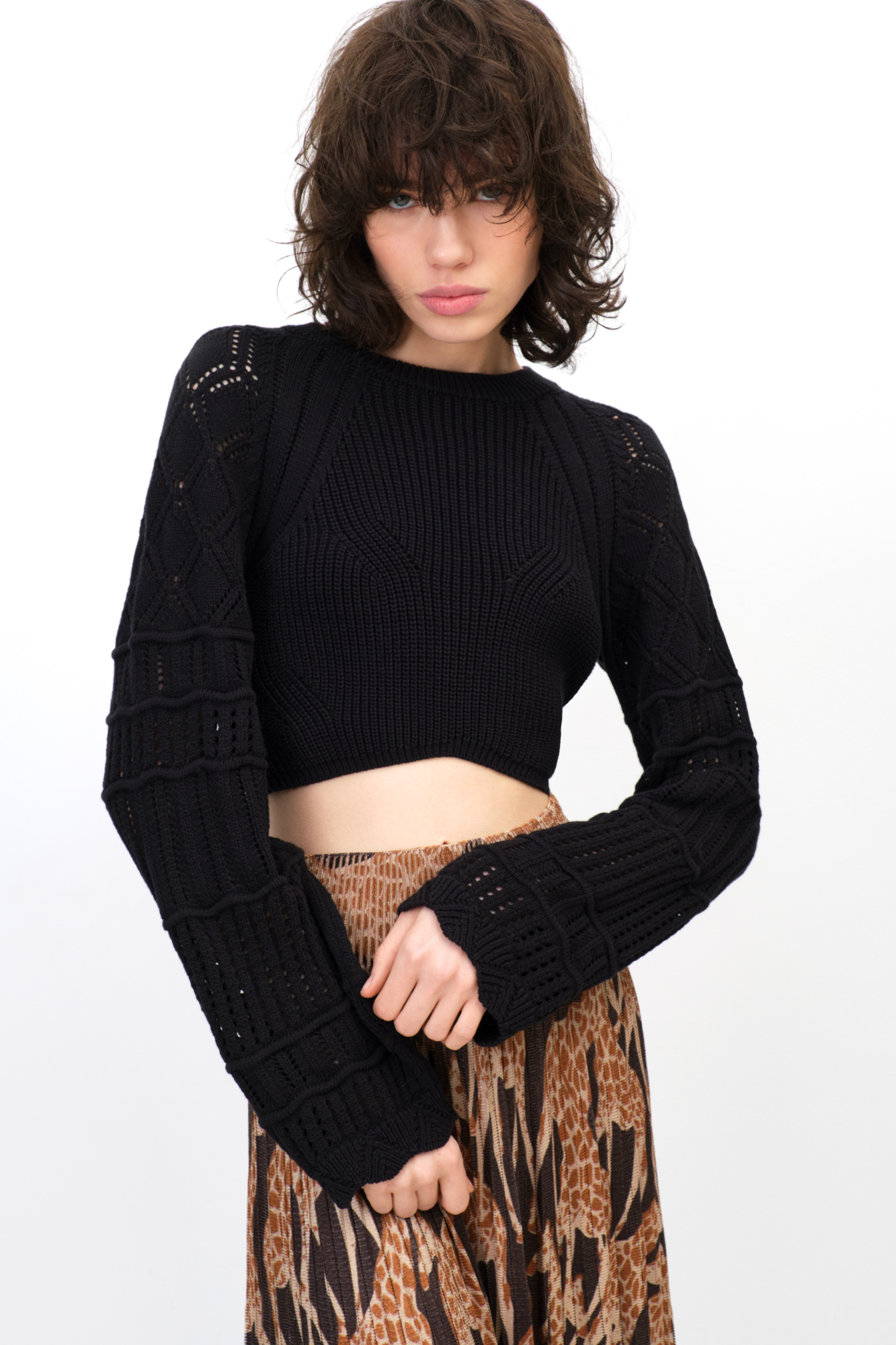 Трикотажный топ фактурной вязки из хлопка. Модель с длинными рукавами. Дополнить образ можно юбкой в таком же стиле.