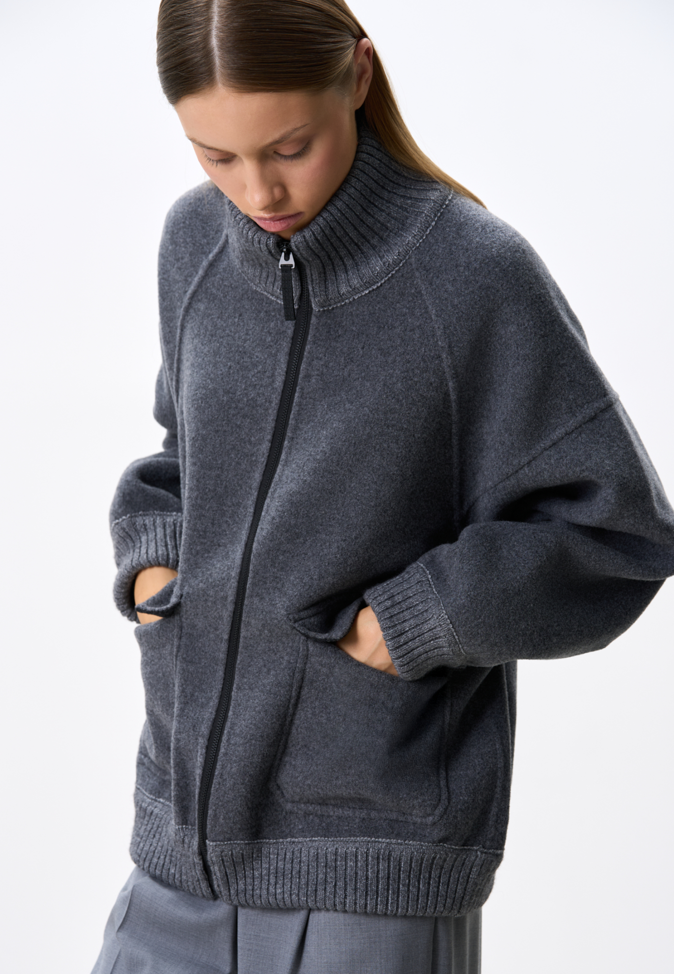 Бомбер из шерсти свободного кроя. Модель со спущенной линией плеч, воротником-стойкой и двумя накладными карманами с клапанами. Воротник, манжеты и низ изделия выполнены из плотного трикотажа в рубчик. Застежка на молнию. Без подкладки.