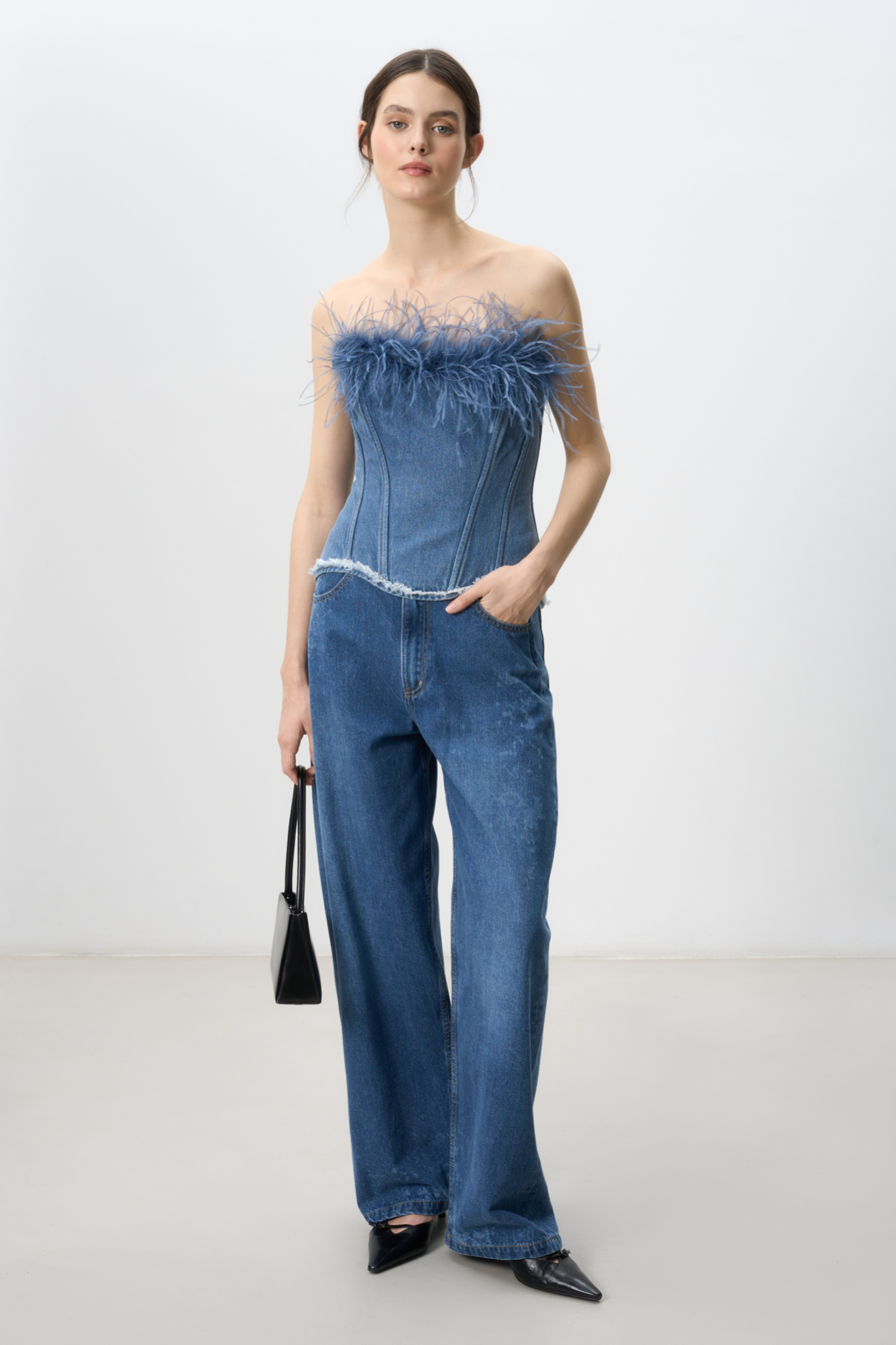 Джинсовый корсет, декорированный лентой со страусиными перьями. Лента с перьями отстегивается. Модель с рельефными швами, контрастной отстрочкой и шнуровкой на спине. Изделие на подкладке.