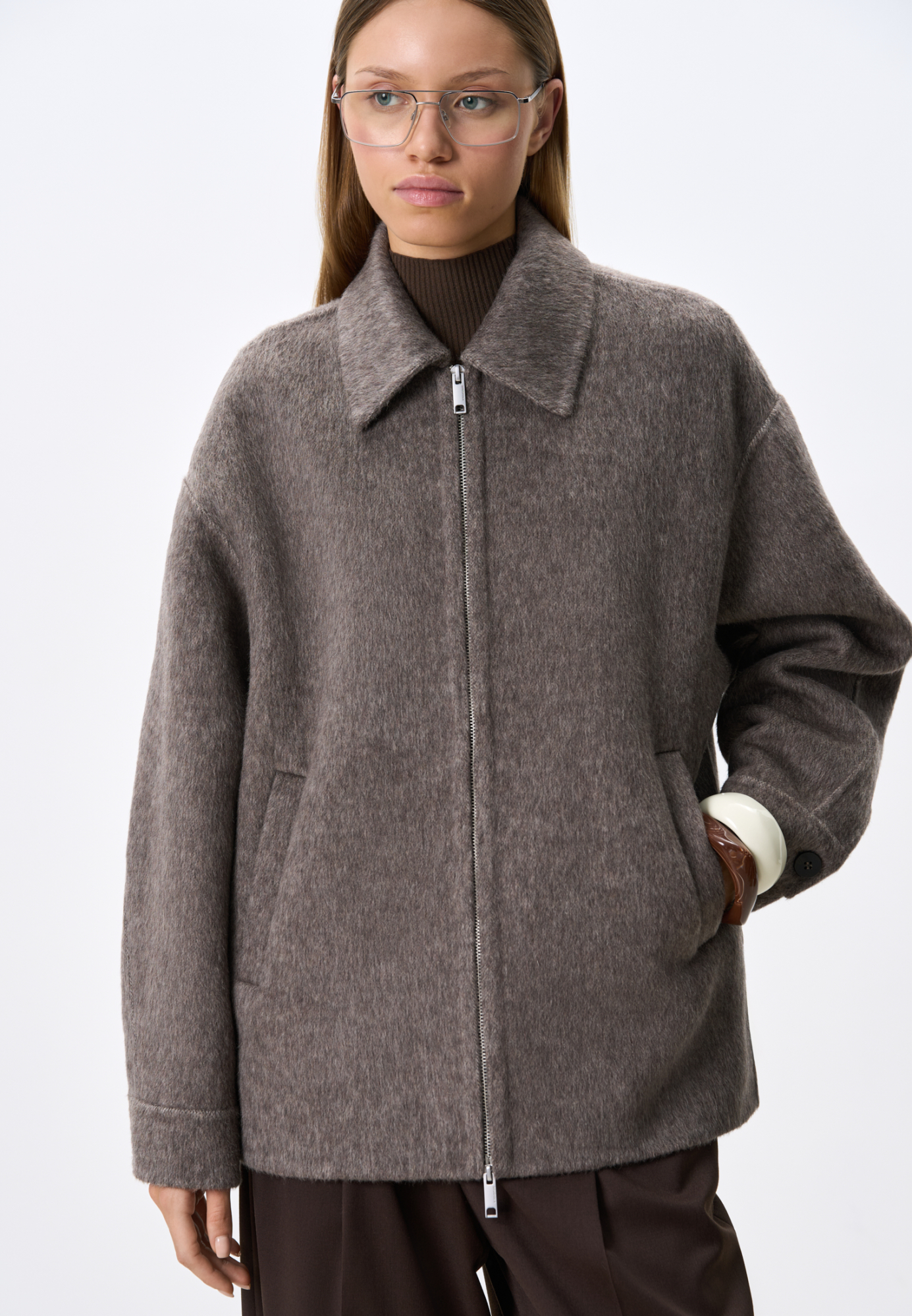 Куртка на молнии из мягкой шерстяной ткани с добавлением верблюжьей шерсти и шелка. Модель свободного кроя с отложным воротником, спущенной линией плеч и двумя боковыми карманами. Застежка на молнию. При пошиве этого изделия была использована технология double face, благодаря которой внутренняя сторона выглядит также аккуратно, как и внешняя.