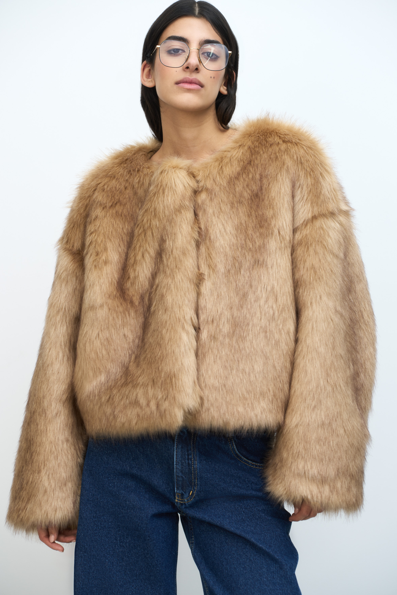 Легкая шуба из искуственного меха со спущенной линией плеча. Круглый вырез. Застежка на крючки.