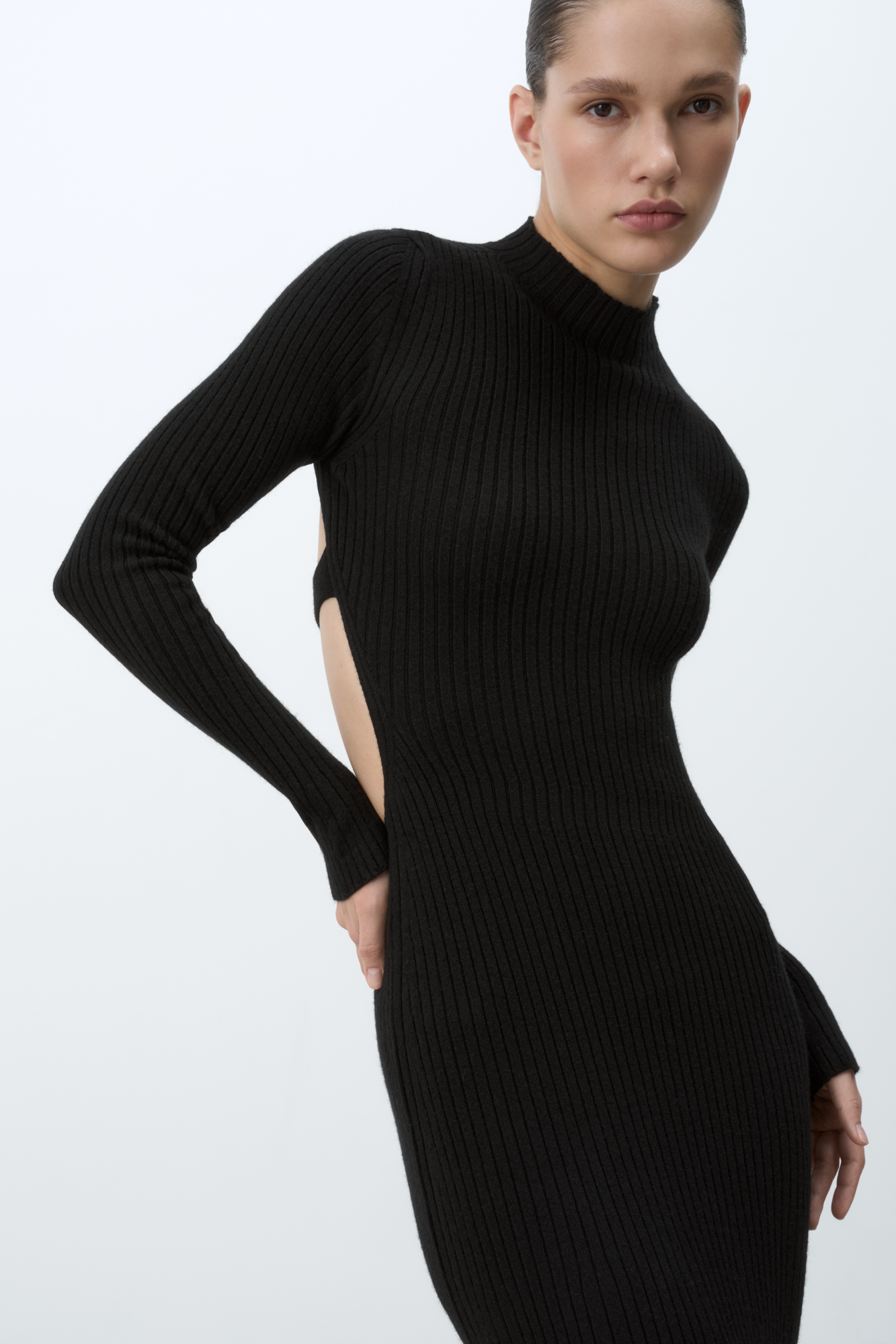 Трикотажное платье из кашемира и шерсти. Модель приталенного силуэта с длинными рукавами, расклешенными рукавами и невысоким воротником. Изделие декорировано глубоким вырезом на спине.