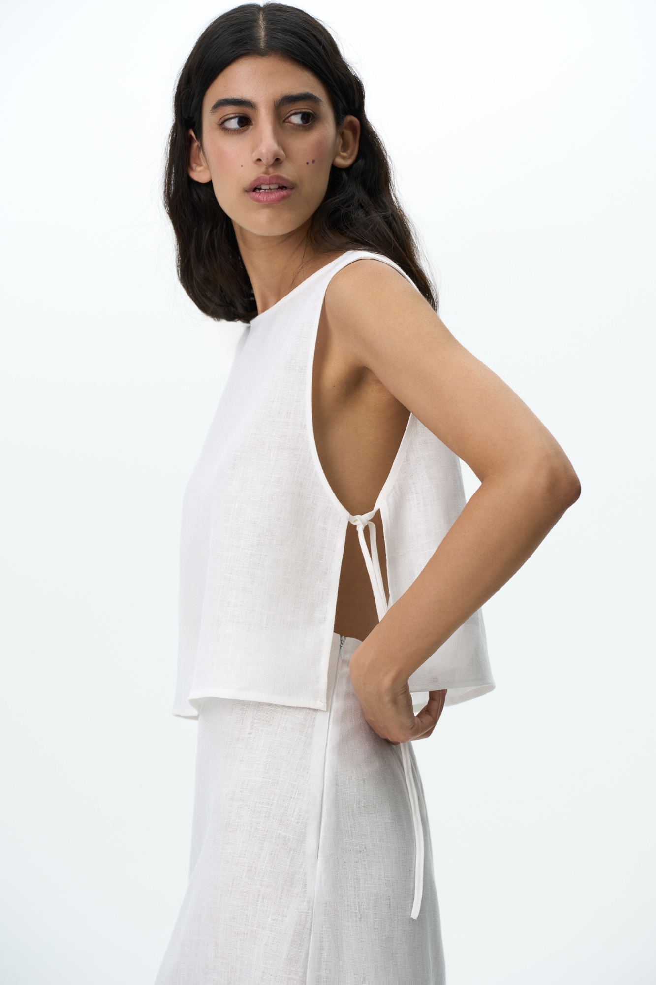 Укороченный топ из 100% льна. Модель свободного кроя, без рукавов, с круглым вырезом горловины. Изделие фиксируется завязками по бокам.