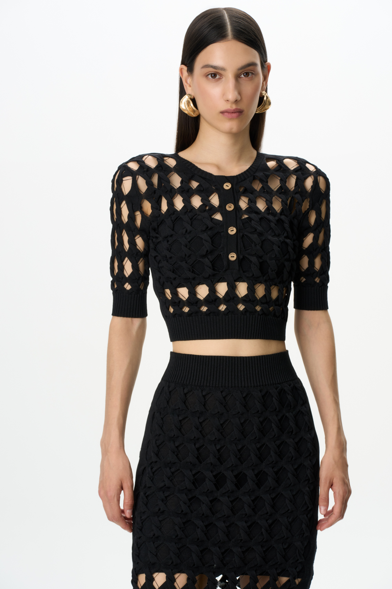 Трикотажный топ с крупным ажурным переплетением. Круглый вырез с планкой на пуговицах. На рукавах и по низу изделия широкая фактурная резинка. В комплекте топ на тонких бретелях.