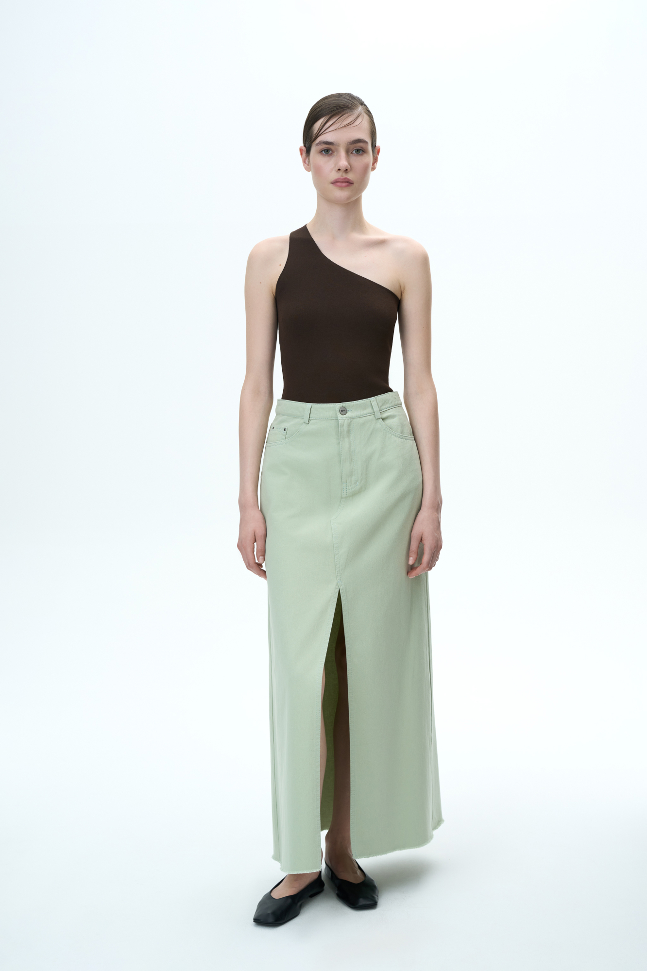 Джинсовая юбка длины макси из 100% хлопка. Модель со средней посадкой, с разрезом спереди и необработанным низом. Застежка на молнию и пуговицу.