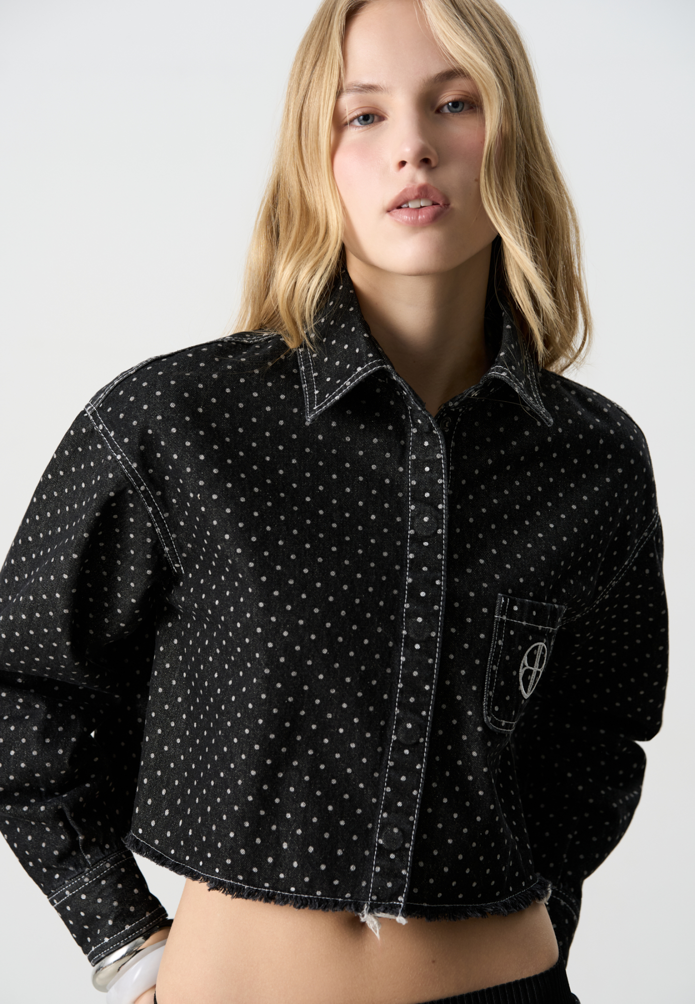 Принтованная джинсовая рубашка из 100% хлопка. Модель укороченного силуэта с удлиненной спинкой, длинными рукавами с манжетами на пуговицах, отложным воротником и нагрудным карманом с вышитым логотипом бренда. Застежка на магнитные пуговицы под планкой. 