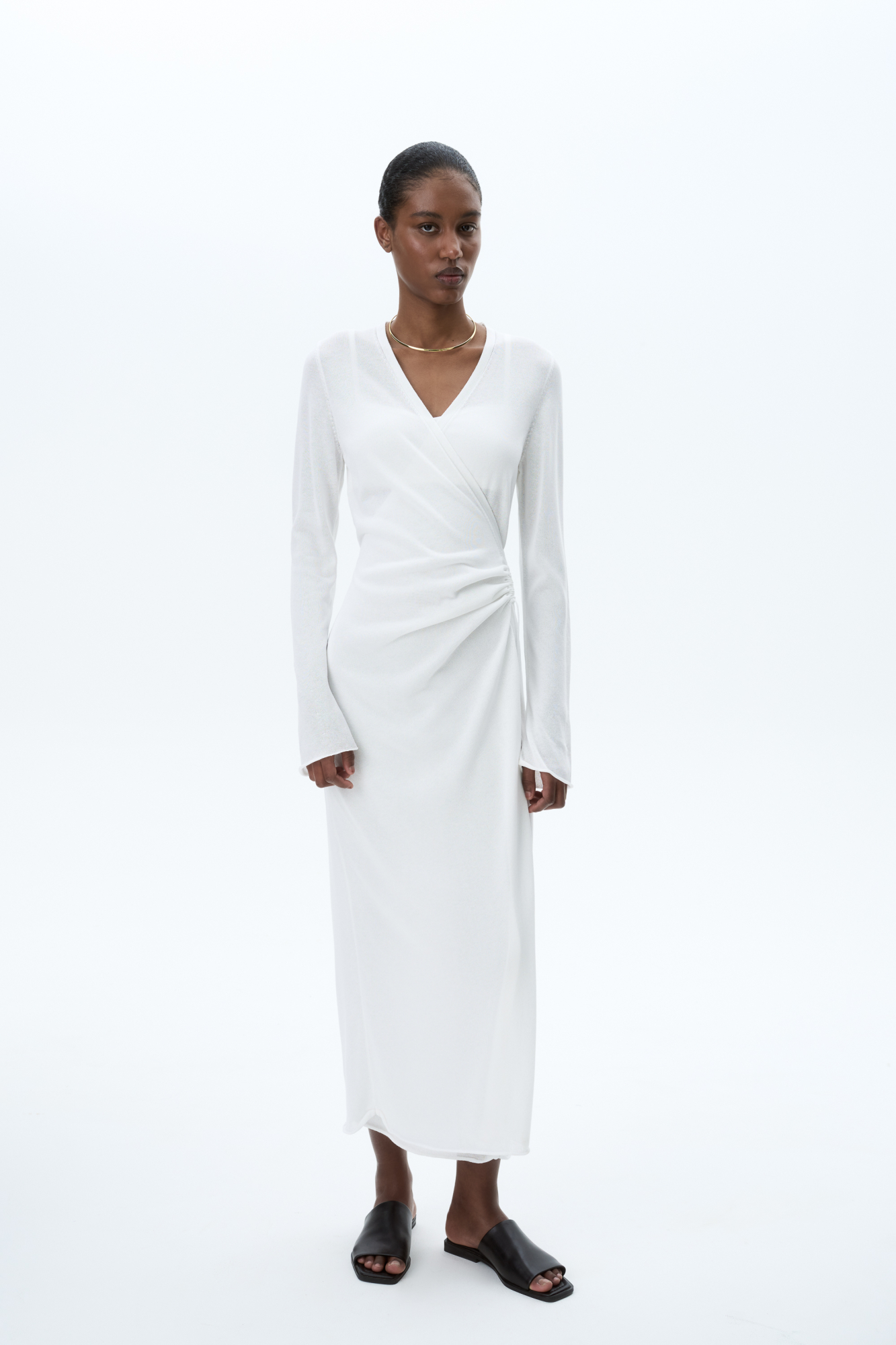 Трикотажное платье длины миди из тонкой вискозы. Модель приталенного силуэта на запах, с V-образным вырезом горловины, длинными расклешенными рукавами и кулиской на талии. 