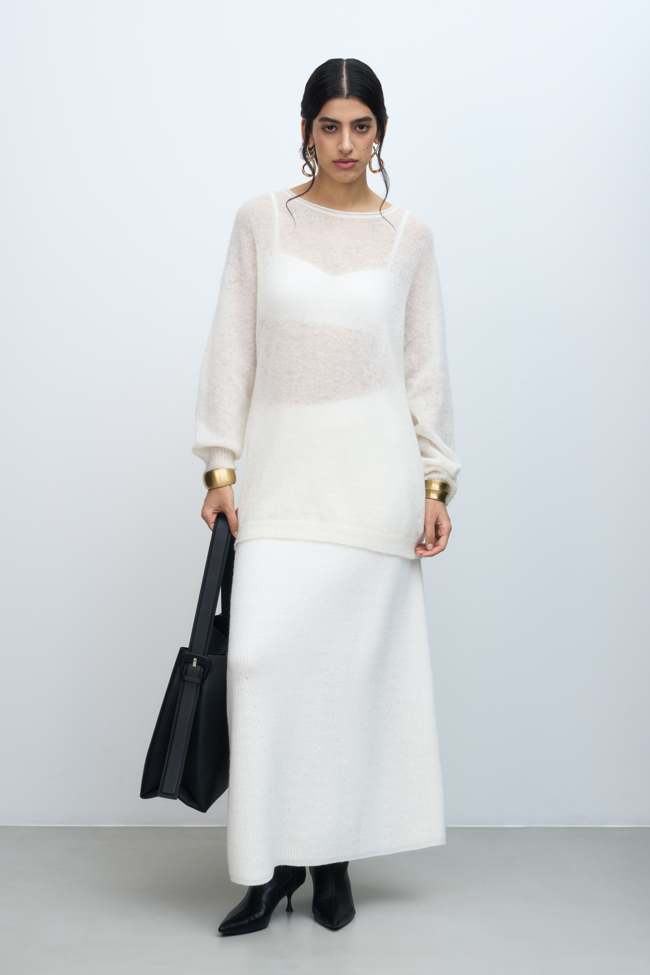 Длинный полупрозрачный трикотажный джемпер из мериносовой шерсти экстрафайн с добавлением шерсти альпака. Модель свободного силуэта, со спущенной линией плеч, длинными рукавами и неглубоким круглым вырезом горловины. Манжеты рукавов и низ изделия выполнены в рубчик.