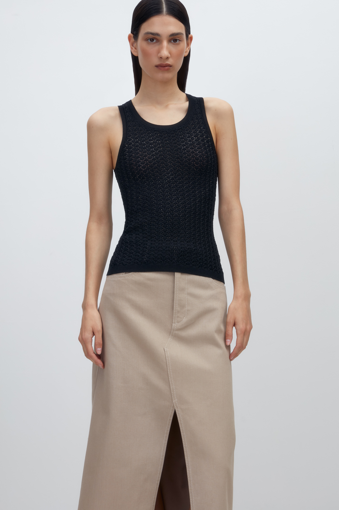 Трикотажный ажурный топ из вискозы с вывязанным орнаментом сердечками. Модель приталенного силуэта, с круглым вырезом горловины, без рукавов, на широких лямках. Края изделия выполнены в рубчик.