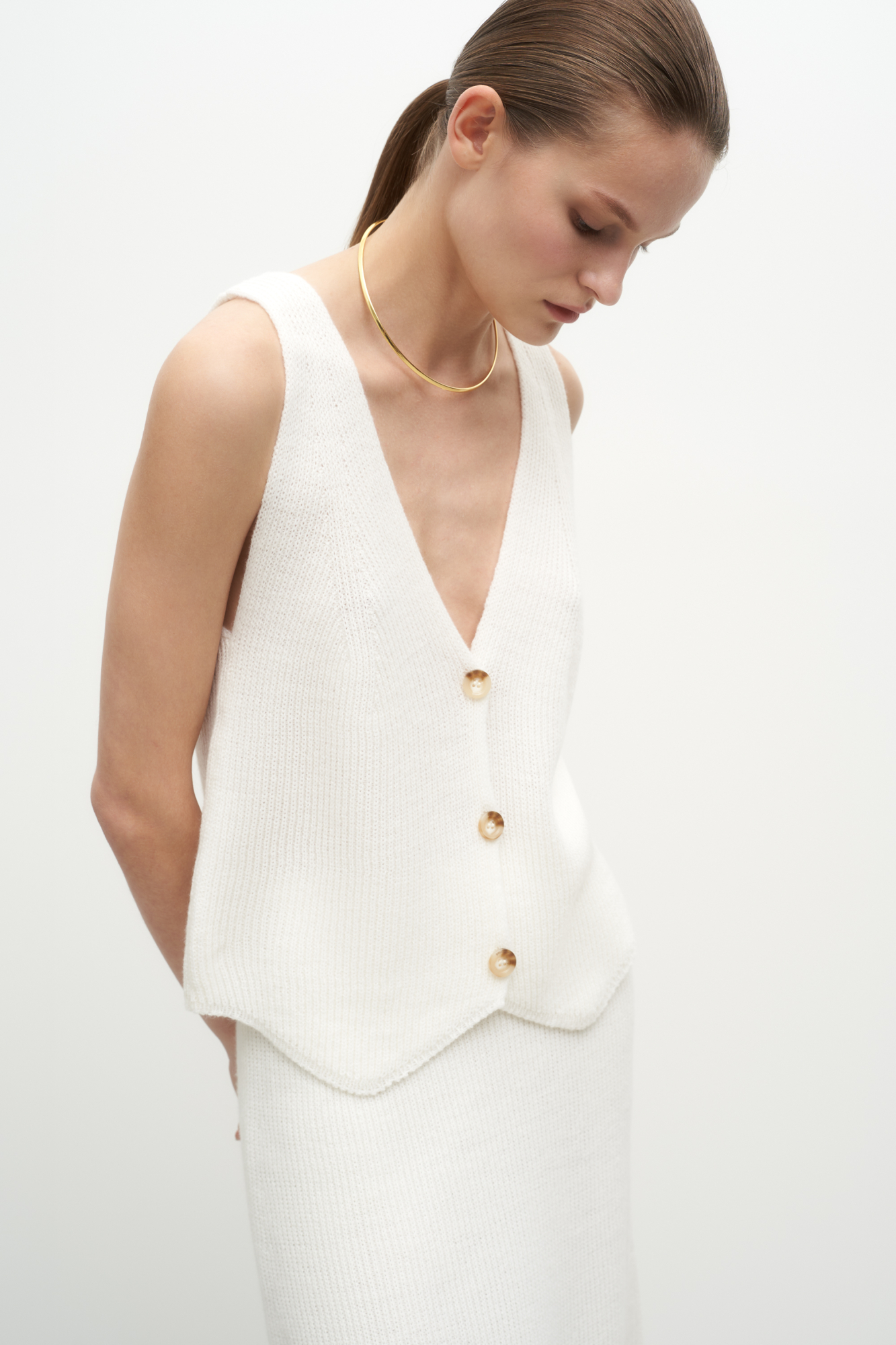 Трикотажный жилет из шерсти. Модель прямого кроя с V-образным вырезом и застежкой на пуговицы. Дополнить образ можно юбкой в таком же стиле.