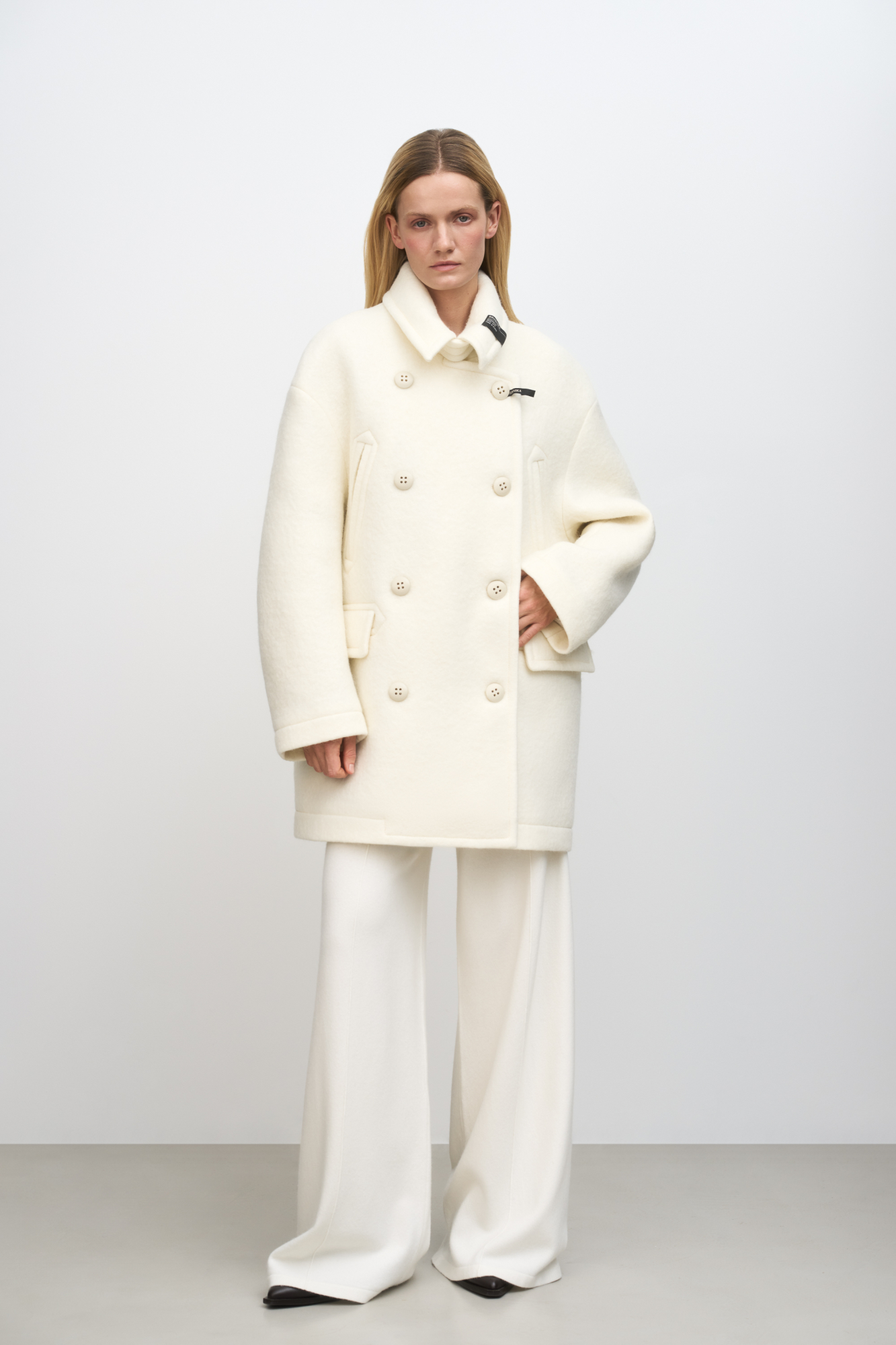 Двубортное пальто из шерсти. <br />
Модель прямого кроя со спущенной линией плеч, карманами на груди и накладными карманами с клапанами. Застежка на пуговицы. Изделие декорировано брендированными ярлыками на воротнике. На подкладке.