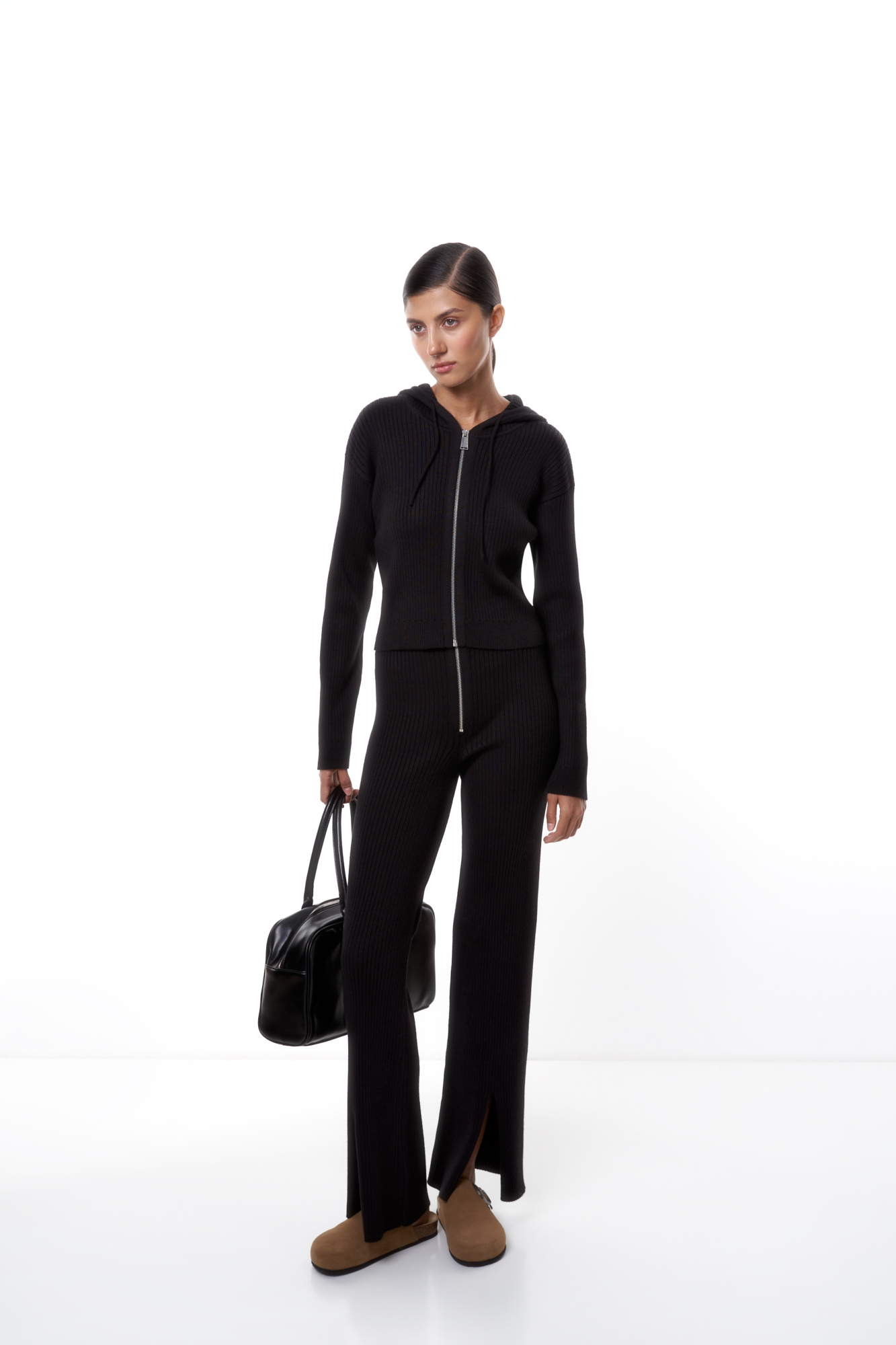 Трикотажные брюки в рубчик. Модель прямого кроя с расклешением к низу и небольшими разрезами спереди. Застежка на молнию. Эластичный пояс на резинке.