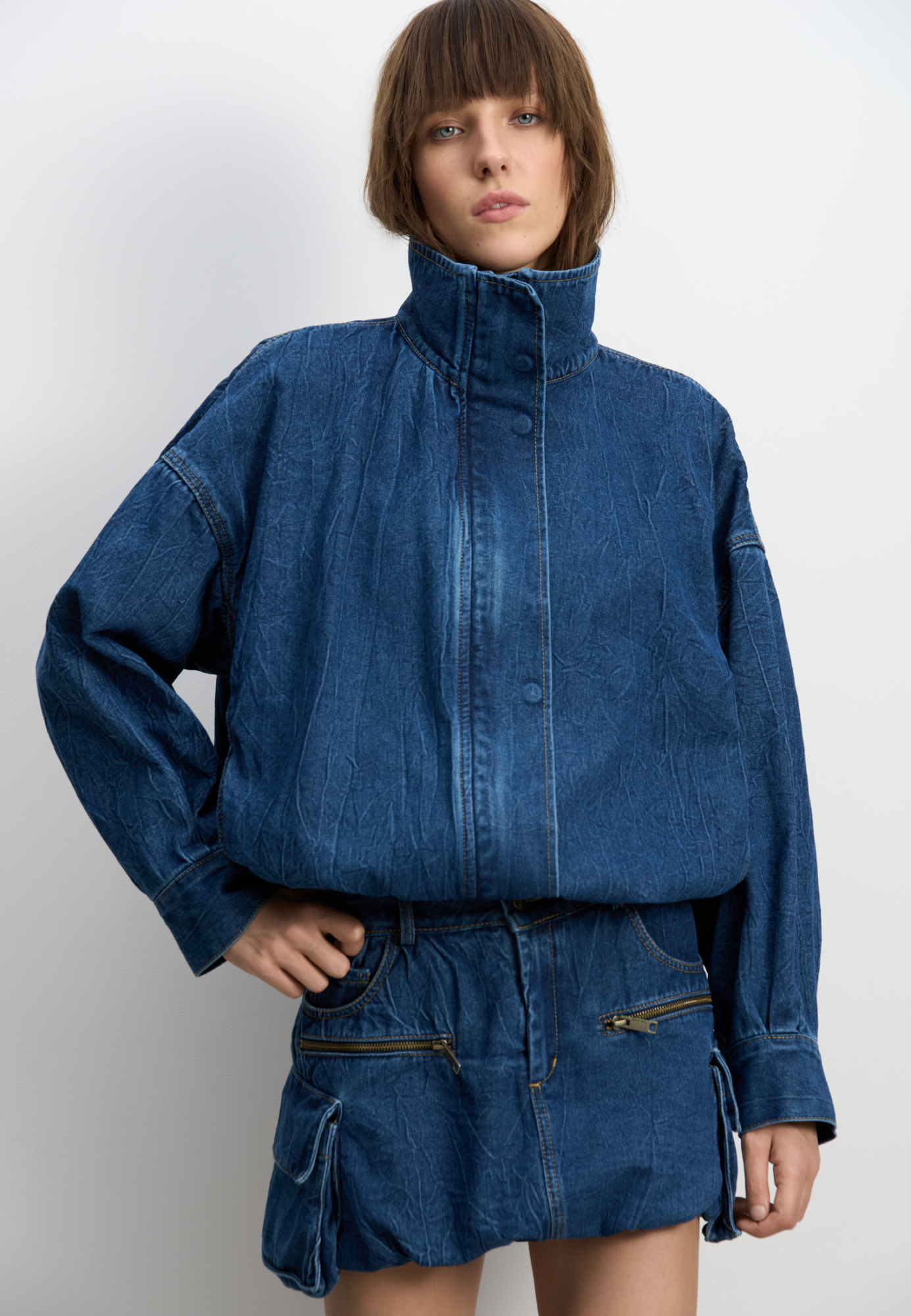 Джинсовый бомбер из 100% хлопка с жатой текстурой. Модель свободного силуэта со спущенной линией плеч, воротником-стойкой, регулируемой кулиской по низу и застежкой на молнию под планкой со скрытыми кнопками.