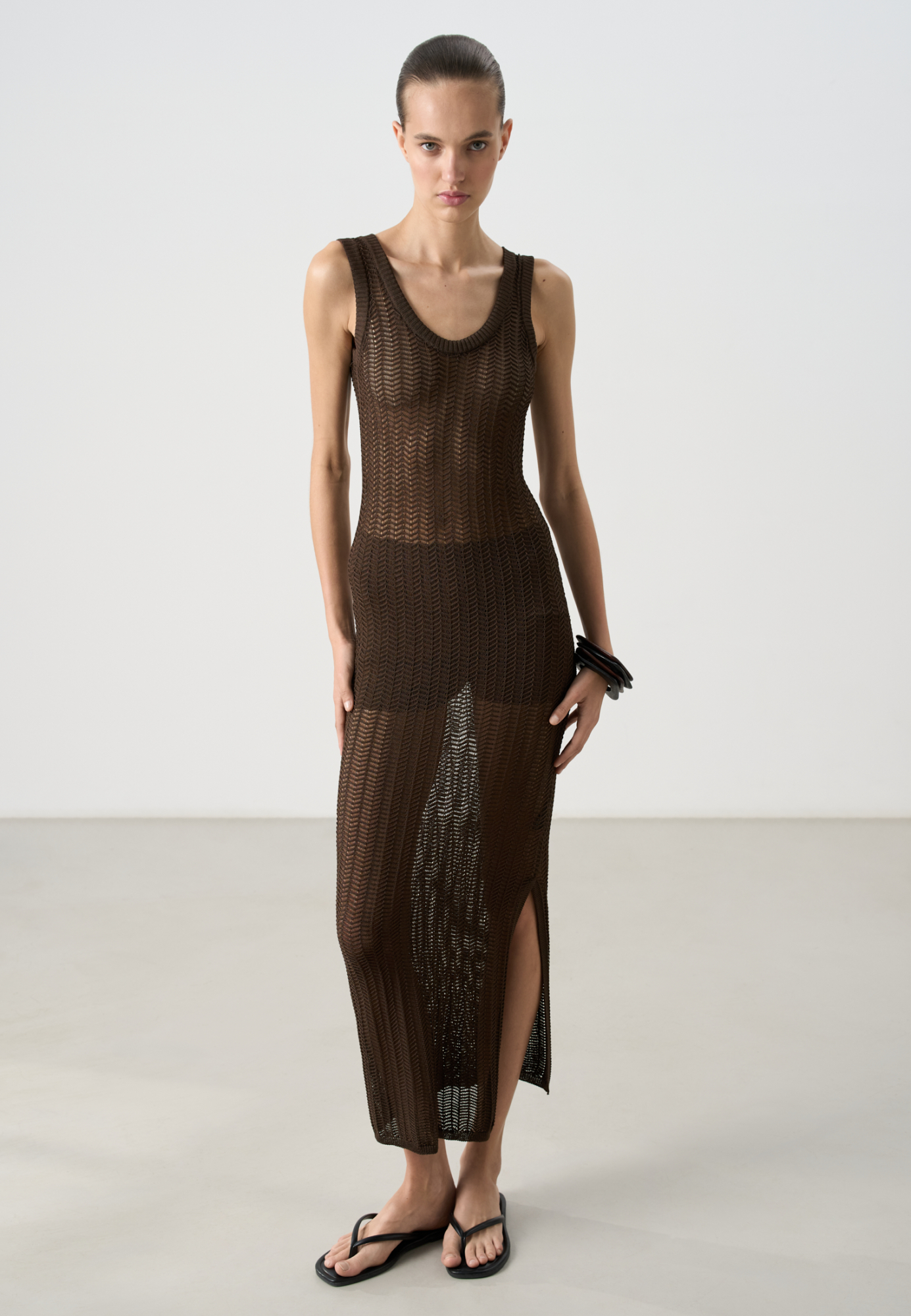 Трикотажный ажурный сарафан из вискозы. Модель свободного силуэта, без рукавов, на тонких бретельках и открытой спиной. Вязка выполнена узором "ёлочка", края изделия выполнены в рубчик.