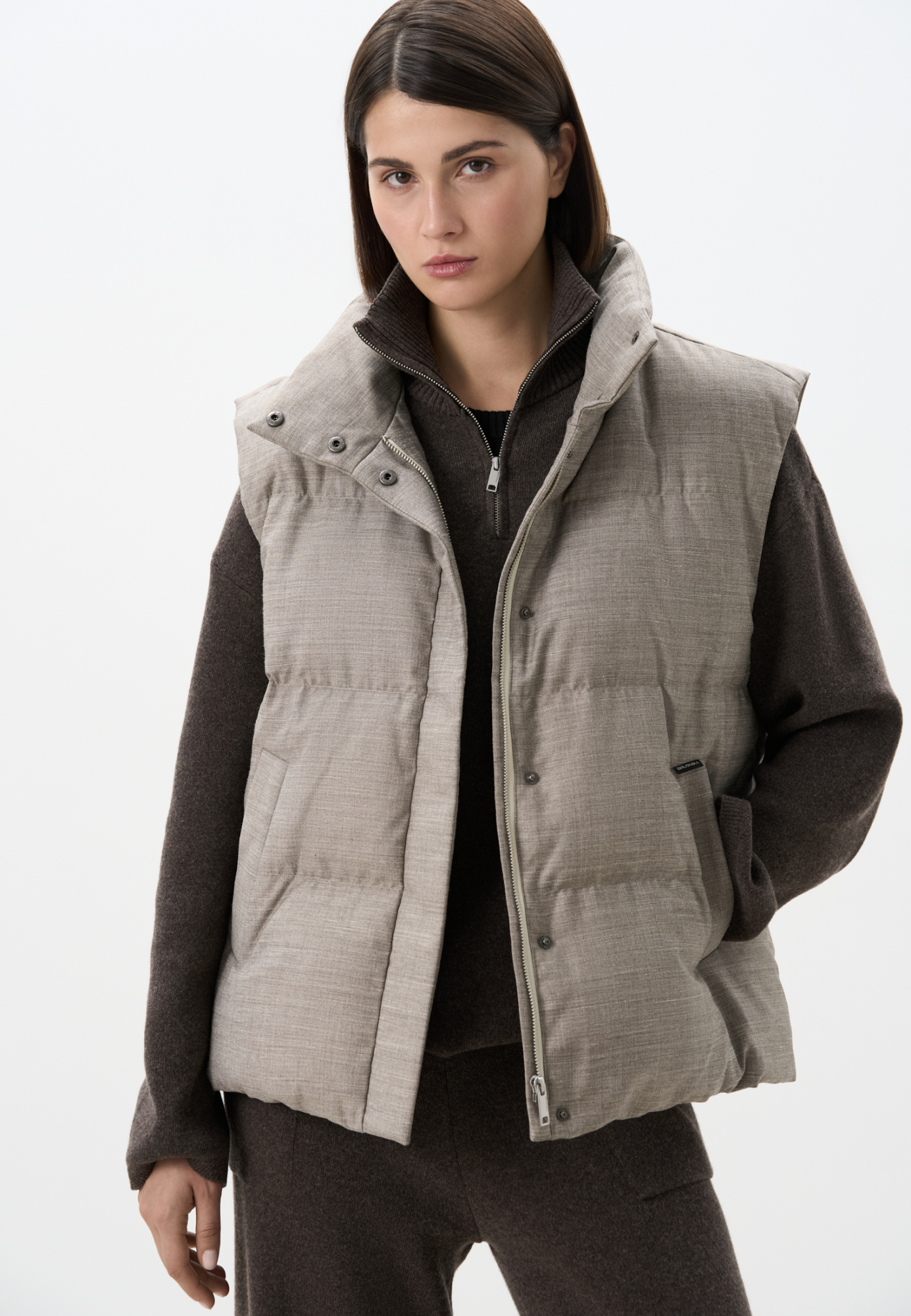 Жилет на пуху с воротником-стойкой. Верх изделия выполнен из смесовой шерсти. Модель свободного силуэта с двумя боковыми карманами. Застежка на молнию и кнопки под планкой. На подкладке. 