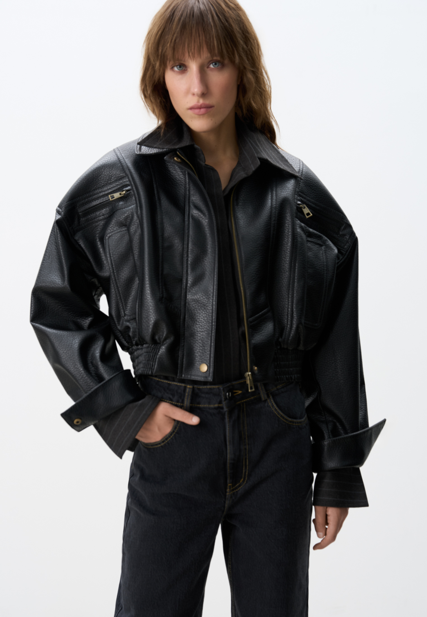 Укороченный бомбер из экокожи.Модель свободного силуэта с длинными рукавами, с воротником и двумя нагрудными карманами. Застежка на молнию. Изделие на подкладке.