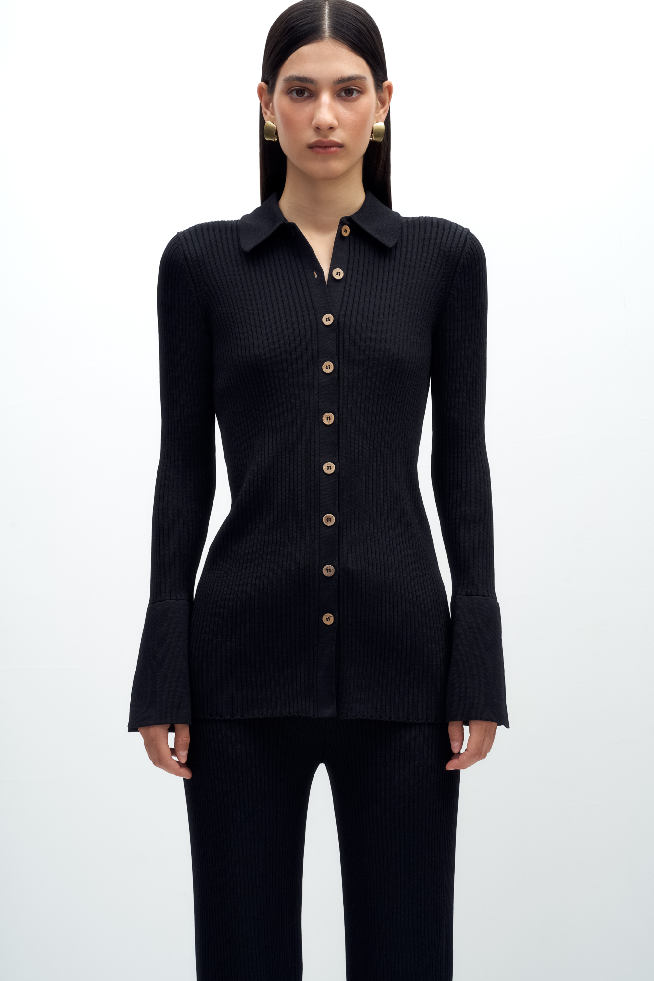 Трикотажный кардиган-рубашка из вискозы. Модель приталенного силуэта, с длинными рукавами, расклешенными манжетами с разрезами, классическим отложным воротником и застежкой на пуговицы.
