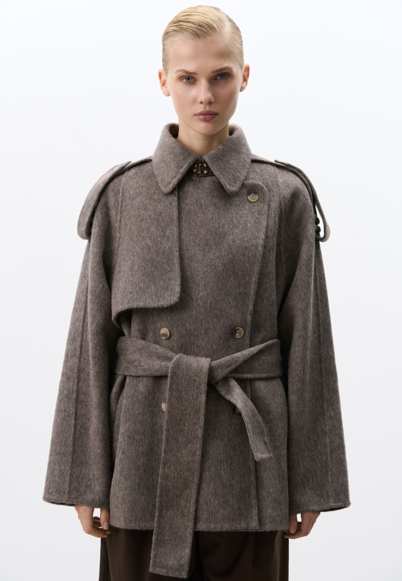 Двубортное пальто с добавлением верблюжьей шерсти. Модель прямого свободного силуэта с отложным воротником и боковыми карманами. Изделие декорировано отлетной кокеткой и широкими лацканами на плечах. На талии расположены шлевки, через которые продевается пояс, выполненный из того же материала, что и пальто. Без подкладки. 