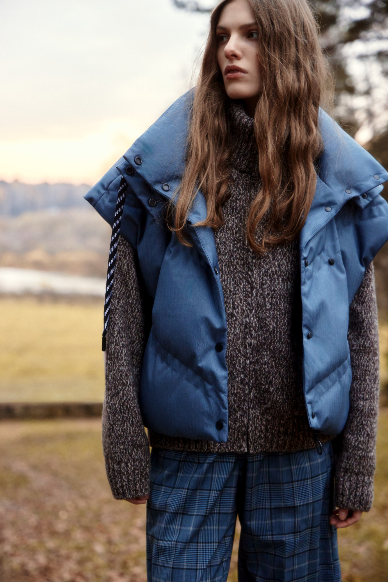 Стеганый жилет на пуху с двойной отстрочкой. Модель с капюшоном и воротником-стойкой. Застежка на кнопки. Низ изделия выполнен на регулируемой кулиске. 