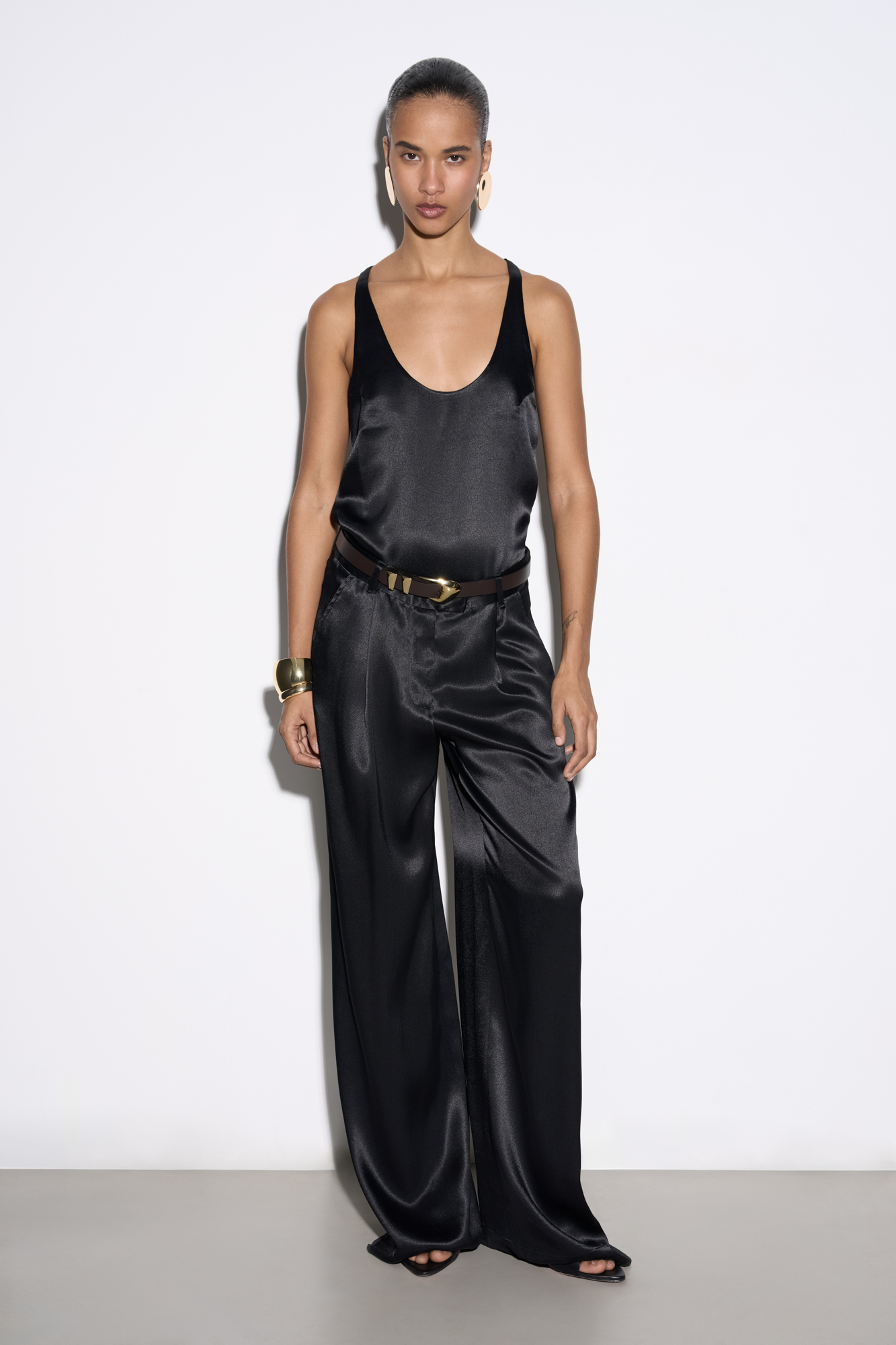 Атласные брюки из 100% вискозы. Модель прямого кроя со шлевками на поясе для ремня, карманами и застежкой на молнию, брючный крючок и пуговицу.