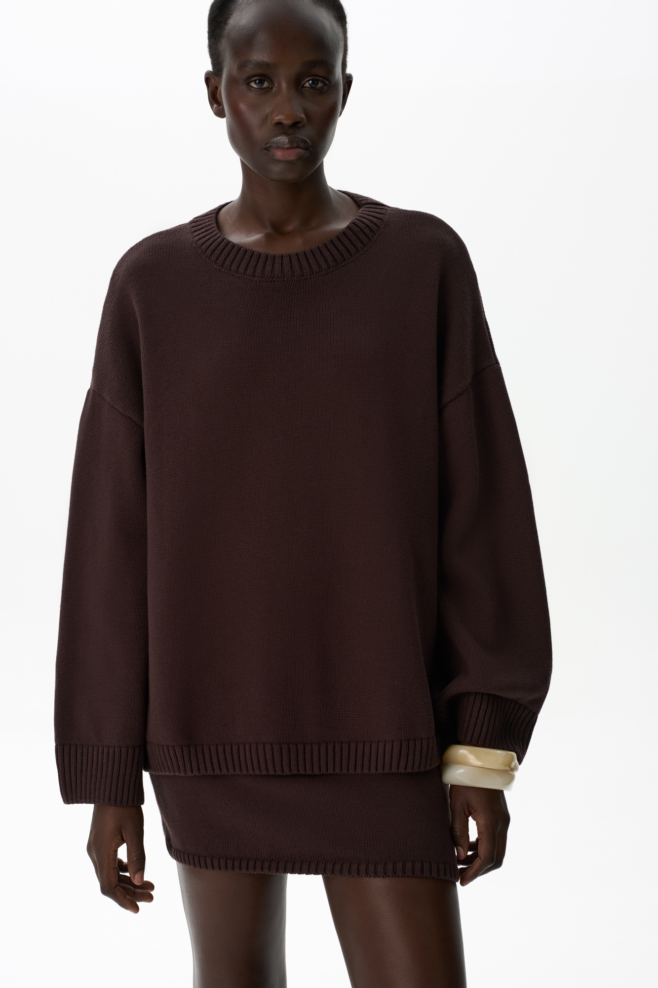 Трикотажный джемпер из 100% хлопка. Модель свободного силуэта со спущенной линией плеч и круглым вырезом горловины. Края изделия выполнены в рубчик. Дополнить образ можно юбкой.