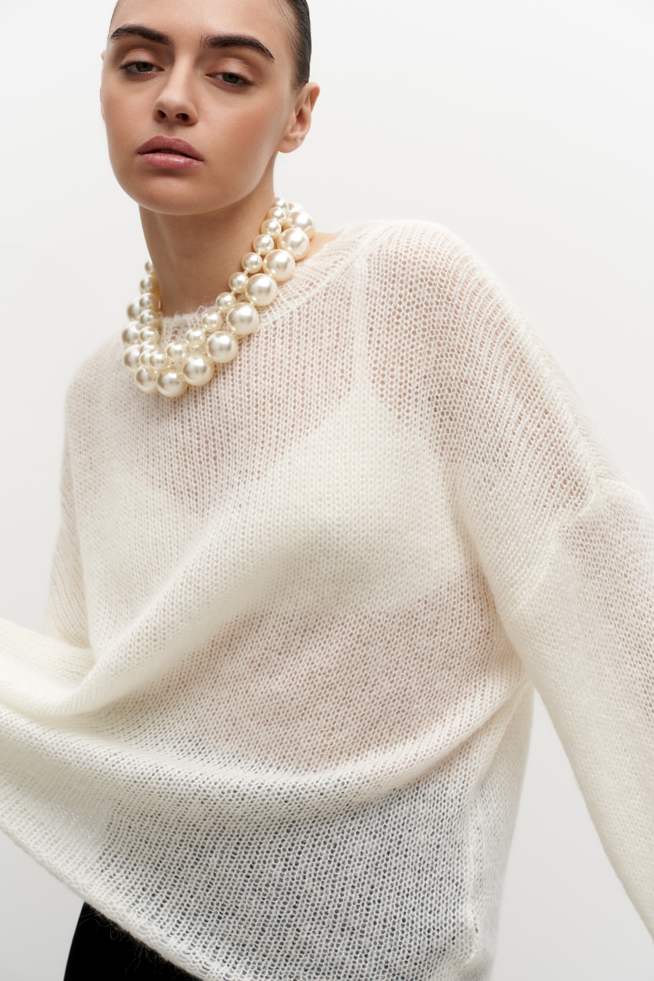 Трикотажный полупрозрачный джемпер из смесовой шерсти с добавлением мохера. Модель свободного силуэта со спущенной линией плеч и круглым вырезом горловины. Манжеты и низ изделия выполнены в широкий рубчик.