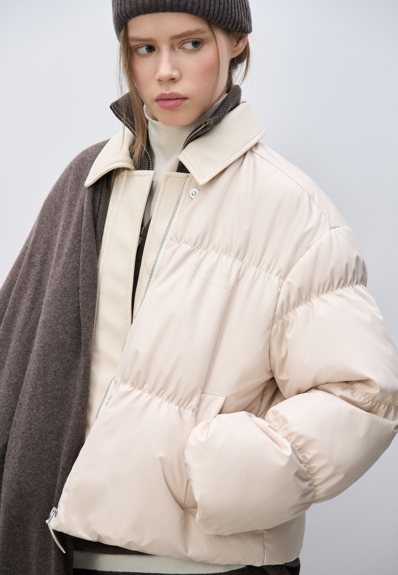 Стеганый пуховик с отложным воротником из экокожи. Модель свободного силуэта со спущенной линией плеч и боковыми карманами. Застежка на молнию и магнитные кнопки под вертикальной планкой из экокожи. Логотип на груди. Изделие выполнено на подкладке.