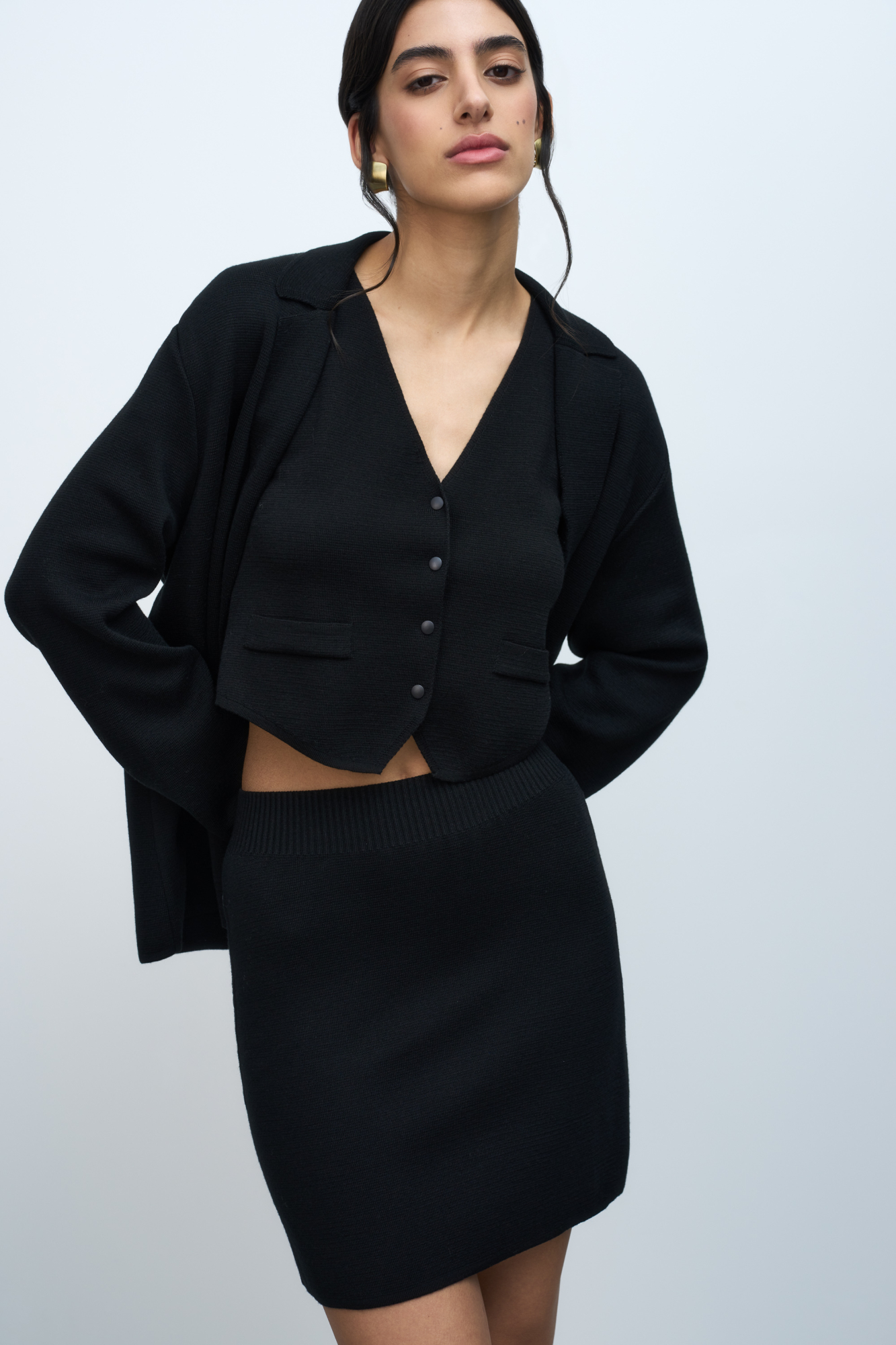 Трикотажная юбка длины мини из шерсти мериноса. Модель с боковой планкой на кнопках, небольшим вырезом сбоку, накладными карманами сзади и широким эластичным поясом на резинке. Дополнить образ можно жилетом, жакетом или бомбером.