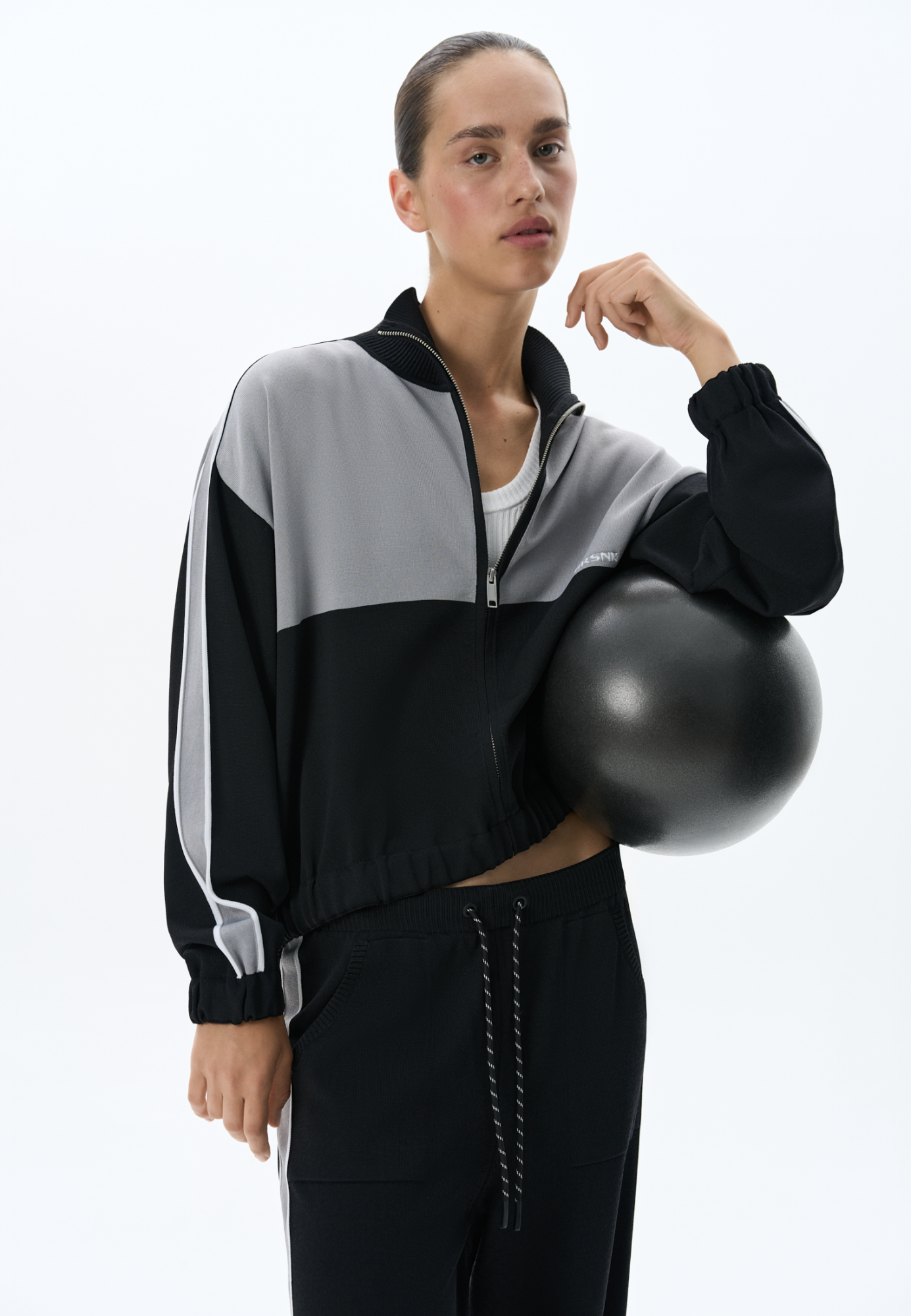 Трикотажный спортивный бомбер из вискозы. Модель прямого силуэта, со спущенной линией плеч, длинными рукавами с широкими лампасами и невысоким воротником-стойкой. Низ изделия и манжеты рукавов выполнены на резинке. Застежка на молнию. Брендированный жаккард на спине.