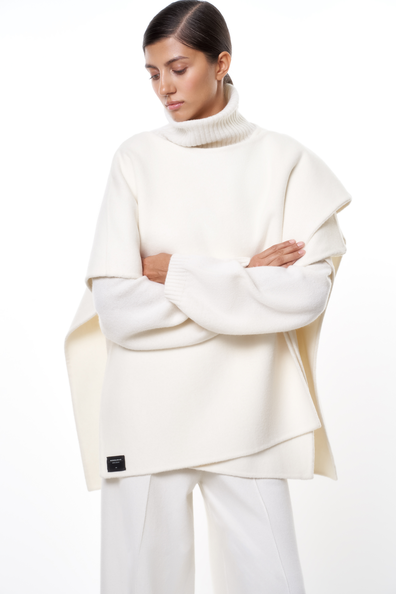 Пончо из шерсти с брендированным ярлыком. Модель oversize, свободного кроя с асимметричным низом. 