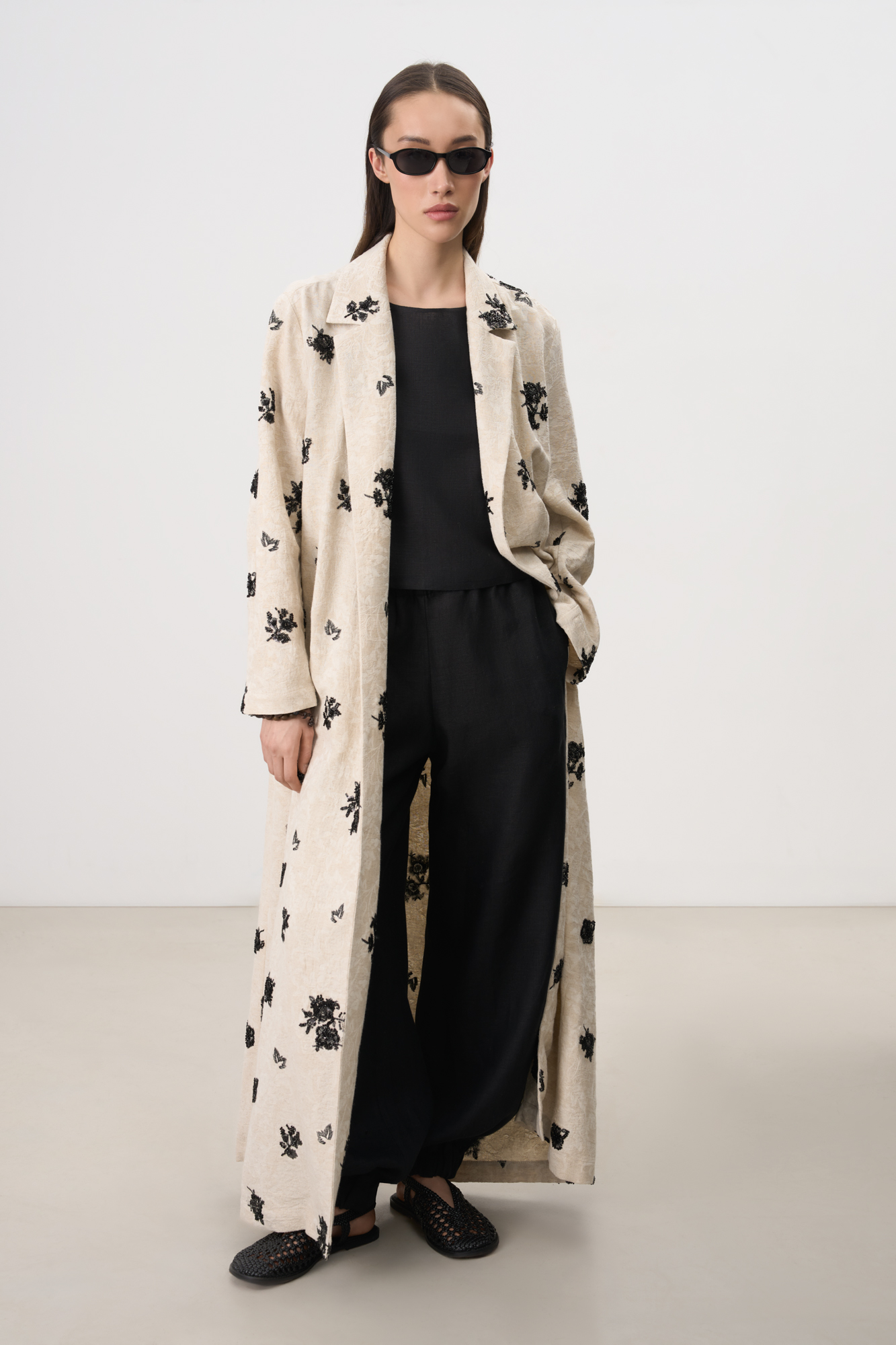 Длинный халат из хлопка и льна. Модель свободного силуэта с длинными широкими рукавами и врезными карманами по бокам. Изделие декорировано жаккардом и вышивкой.