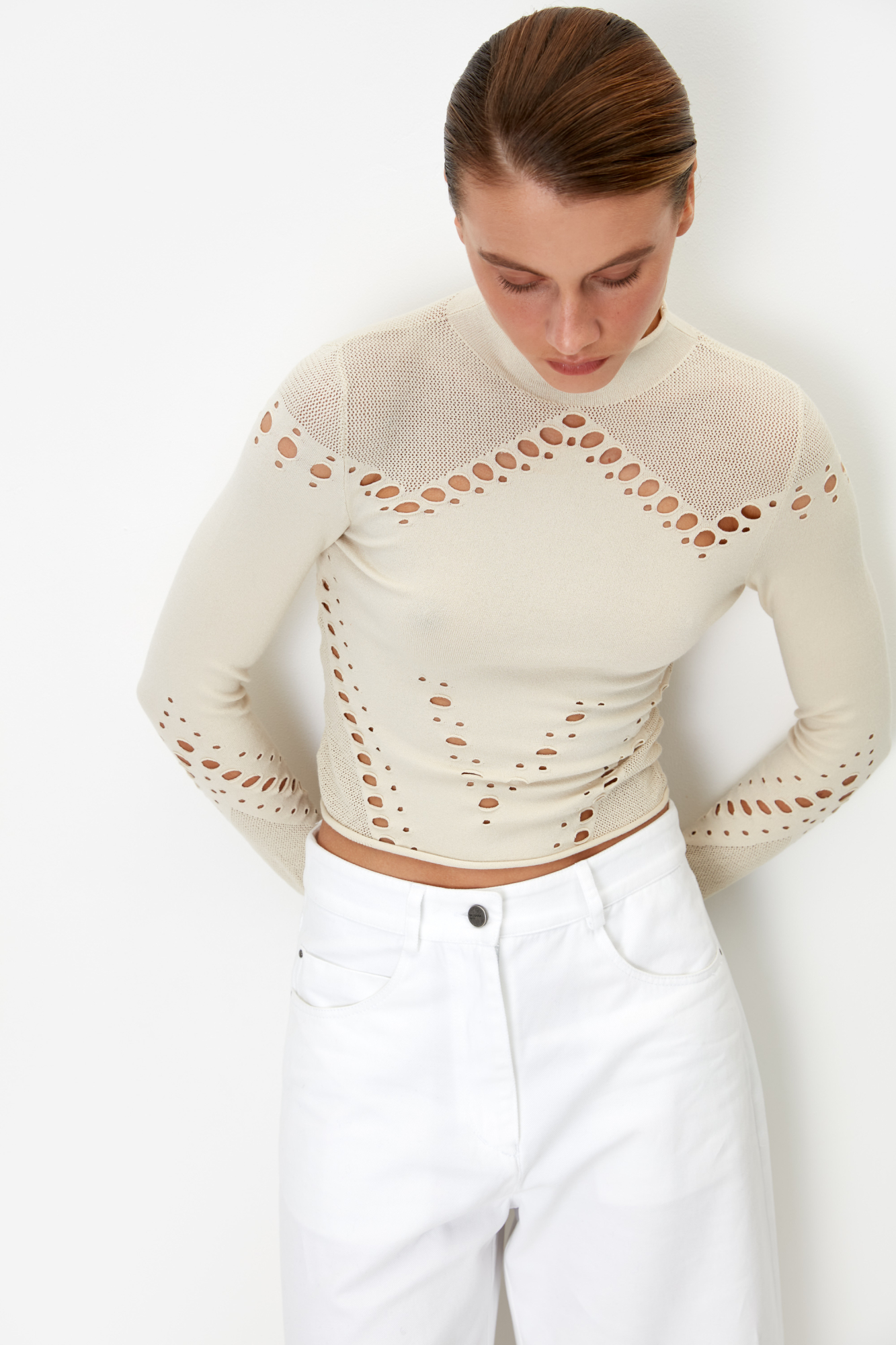 Трикотажная укороченная водолазка из тонкой эластичной вискозы. Модель облегающего силуэта, с длинными рукавами и невысоким воротником-стойкой. Изделие выполнено в комбинированной технике вязки, сочетающей гладь и сетку. Водолазка декорирована вырезами, создающими геометрический узор.<br />
