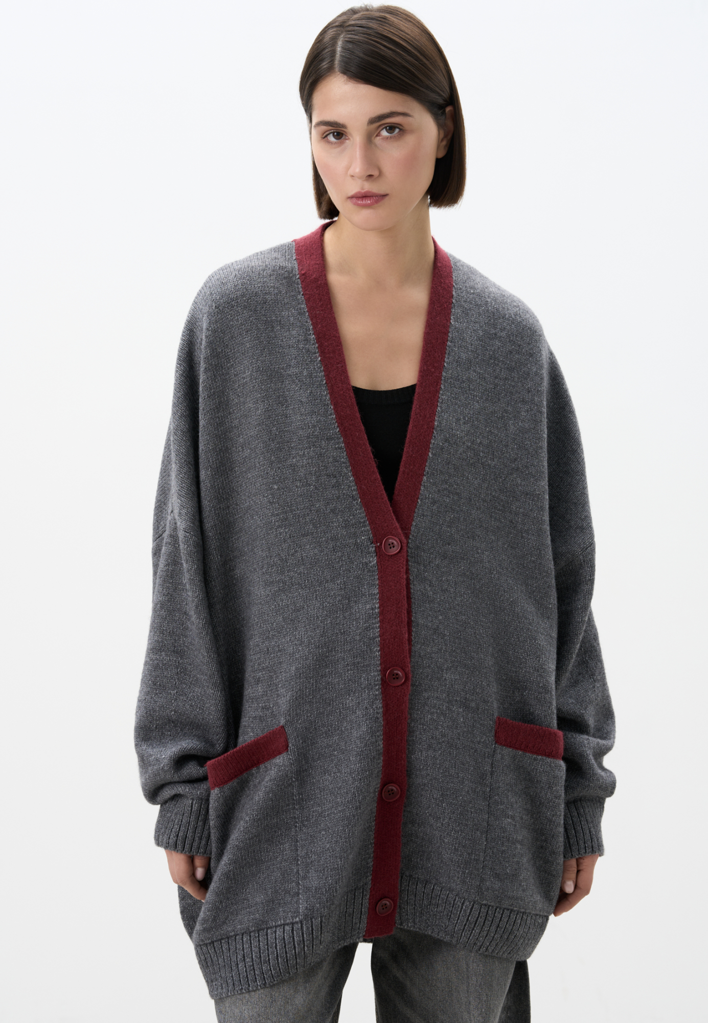 Трикотажный кардиган из шерсти альпака. Модель свободного силуэта, с длинными рукавами, спущенной линией плеч, V-образным вырезом, накладными карманами и застежкой на пуговицы. Изделие декорировано планкой и карманами контрастного цвета.