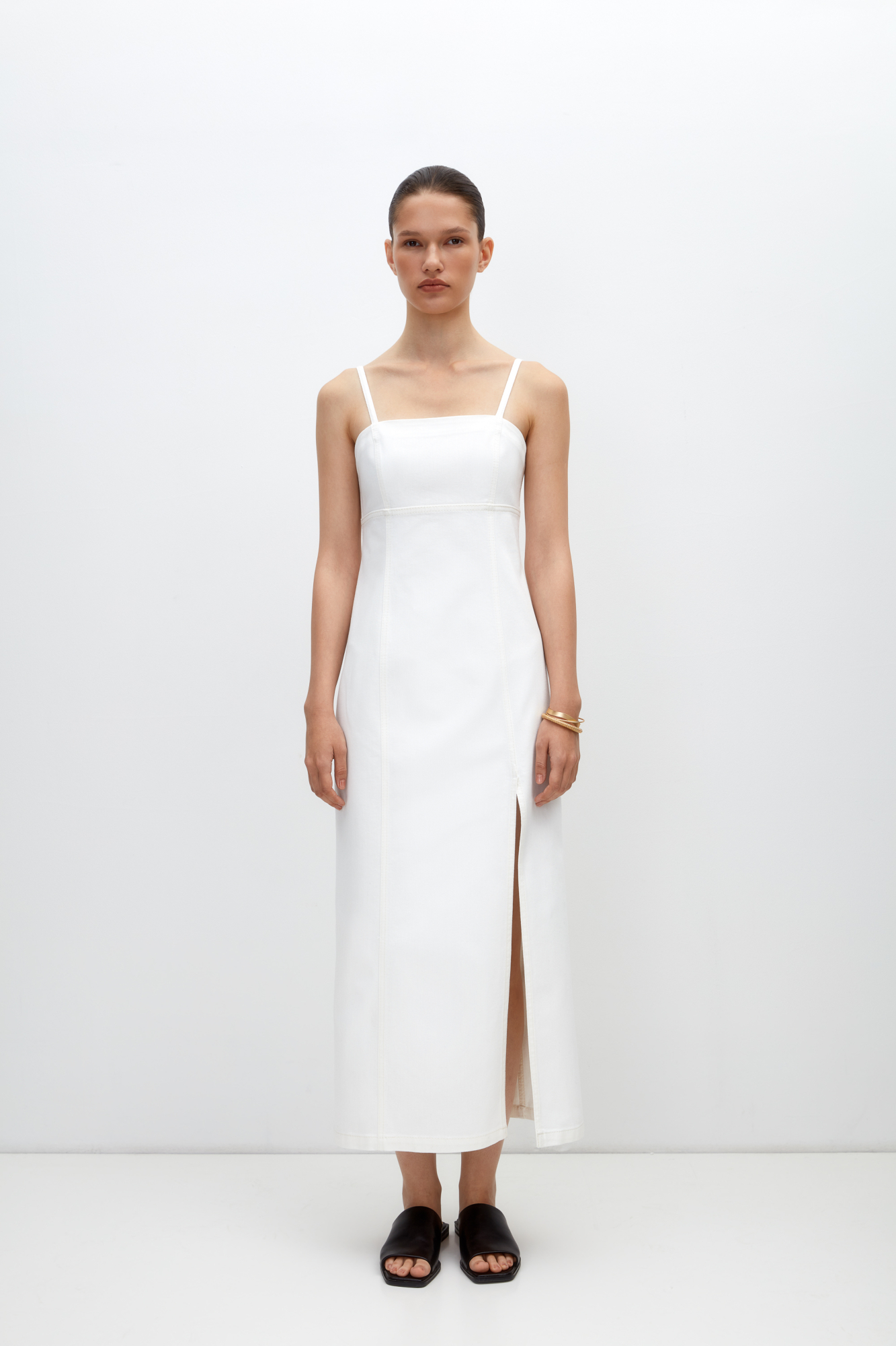 Джинсовый сарафан из 100% хлопка с разрезом от бедра. Модель приталенного силуэта, на тонких регулируемых бретелях. С застежкой на молнию сзади. 