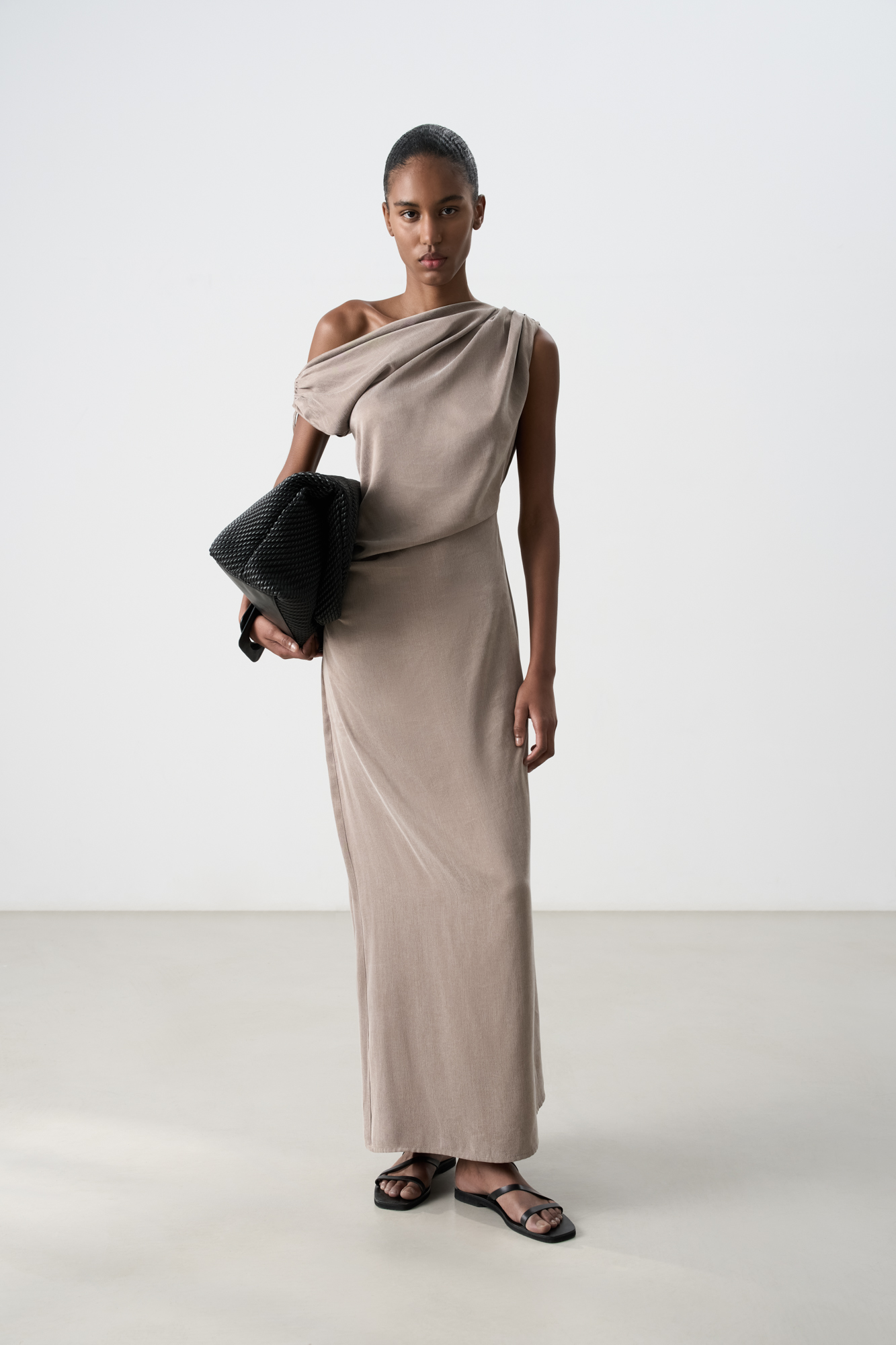Платье из купры длины макси. Модель приталенного силуэта, без рукавов, с асимметричным вырезом горловины, драпировкой на плече и талиии. Высокий разрез сбоку.