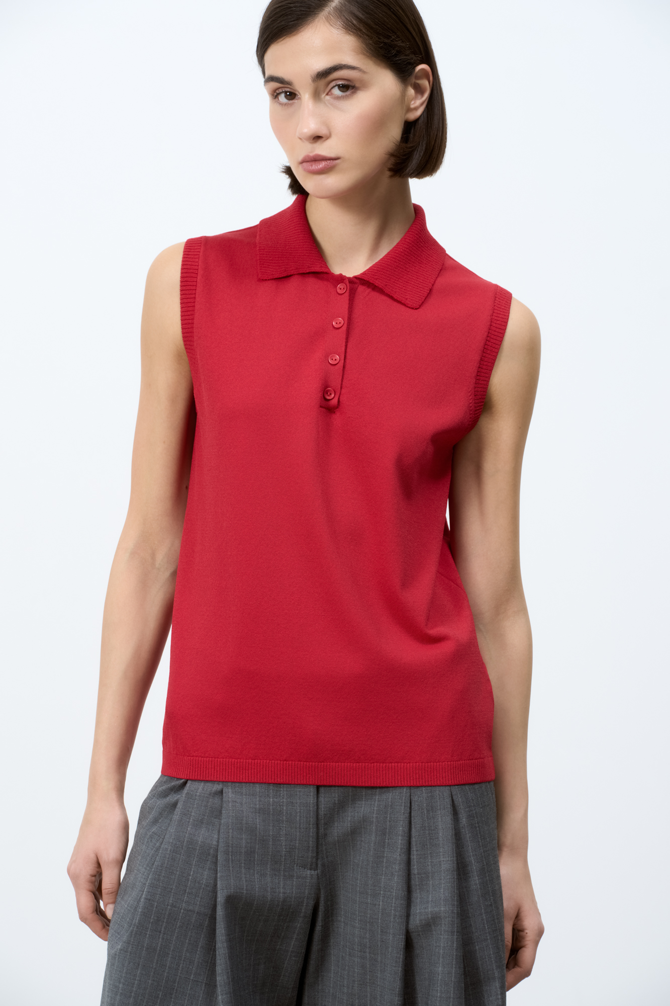 Трикотажный топ с воротником-поло. Модель приталенного силуэта, застежка на пуговицы. Края изделия в рубчик.
