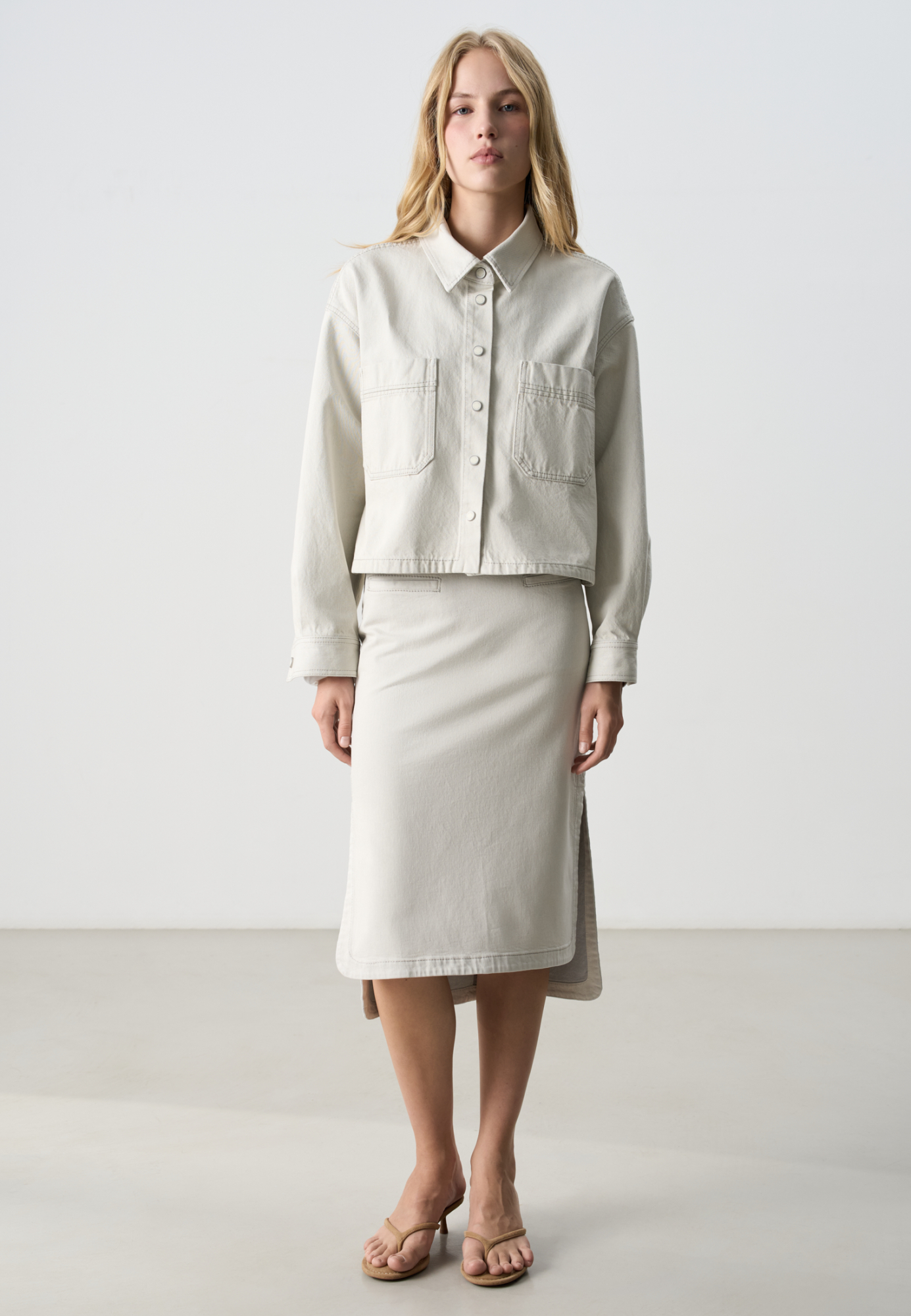 Джинсовая юбка длины миди из 100% хлопка. Модель прямого кроя, с высокими разрезами по бокам и удлиненным подолом сзади, создающим асимметрию. Застежка на молнию сзади.