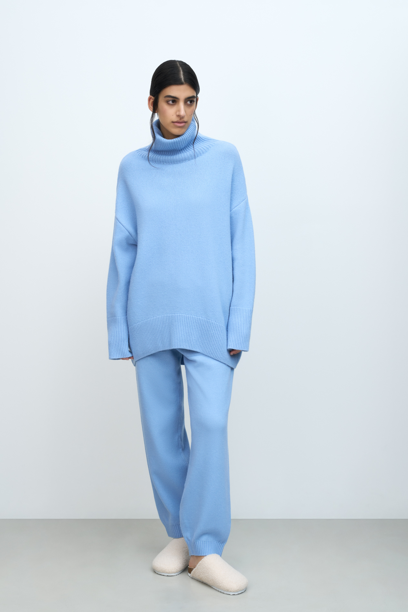 Трикотажный джемпер из мягкой шерсти с добавлением кашемира. Высокий ворот, заниженная линия плеч, удлиненная спинка. Края изделия сделаны в широкий рубчик. Можно дополнить комплектными брюками.