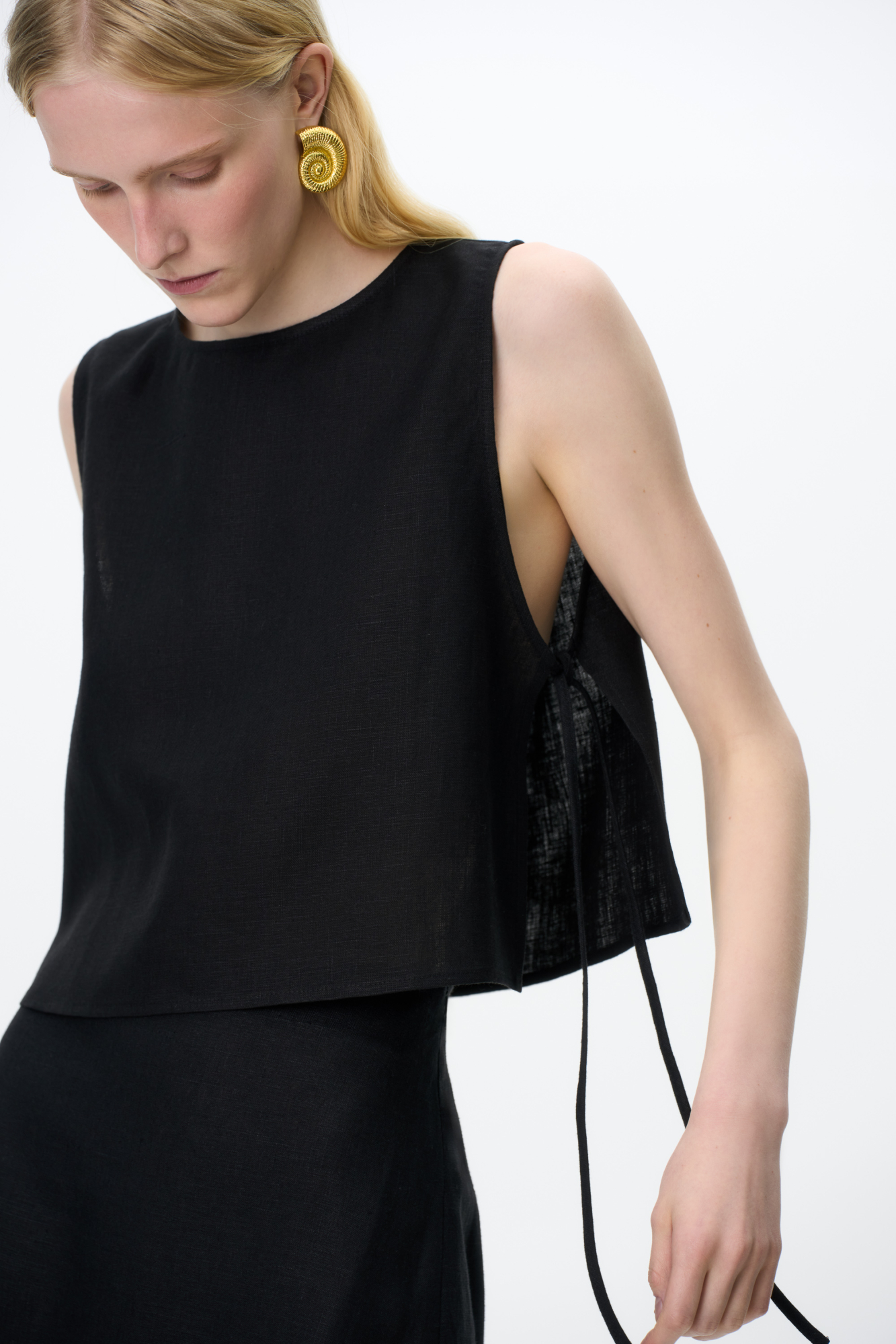 Укороченный топ из 100% льна. Модель свободного кроя, без рукавов, с круглым вырезом горловины. Изделие фиксируется завязками по бокам.