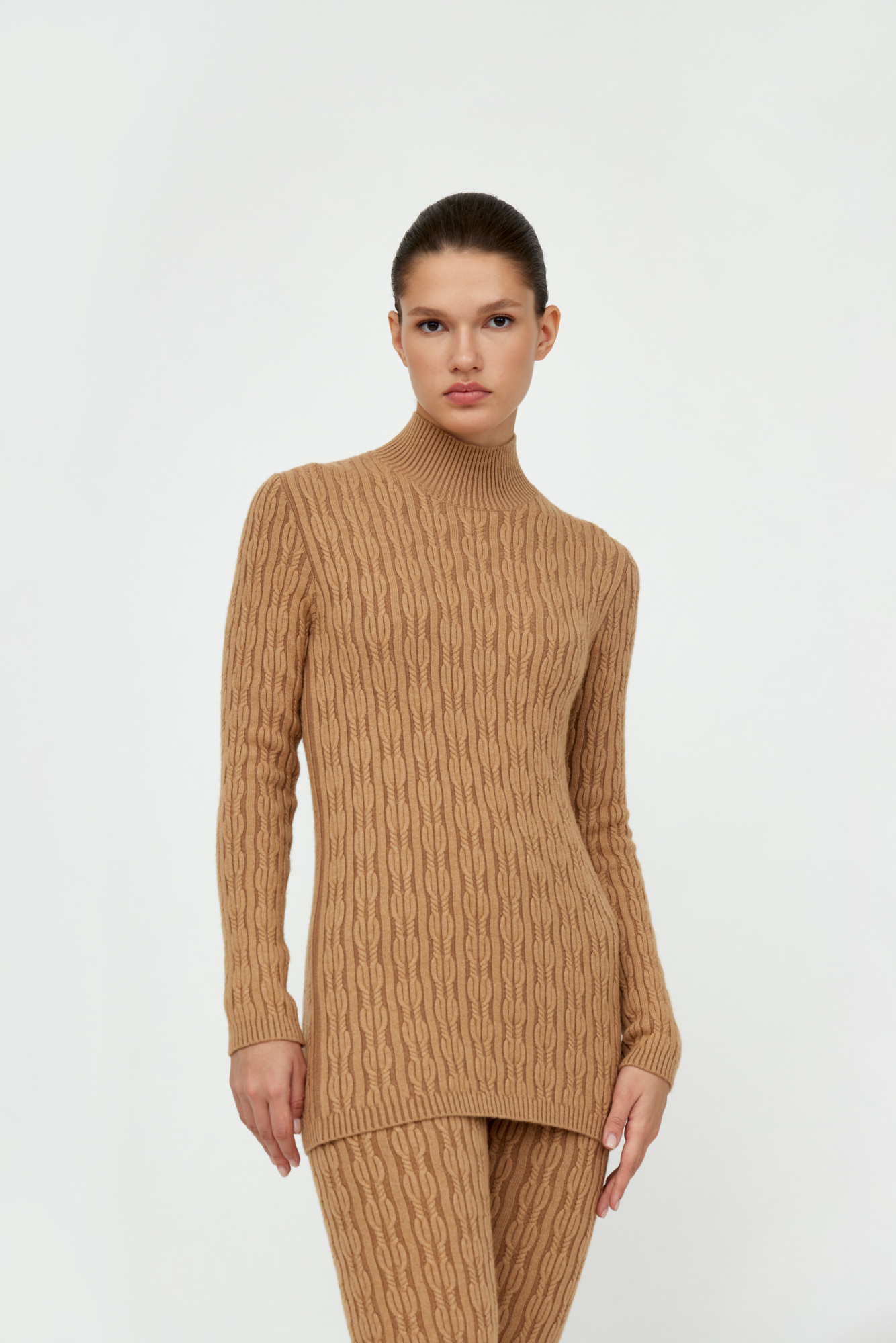 Трикотажная водолазка из шерсти и кашемира. Модель по фигуре, с длинными рукавами и невысоким воротником-стойкой в рубчик. Изделие декорировано вывязанным узором в виде объемных кос.