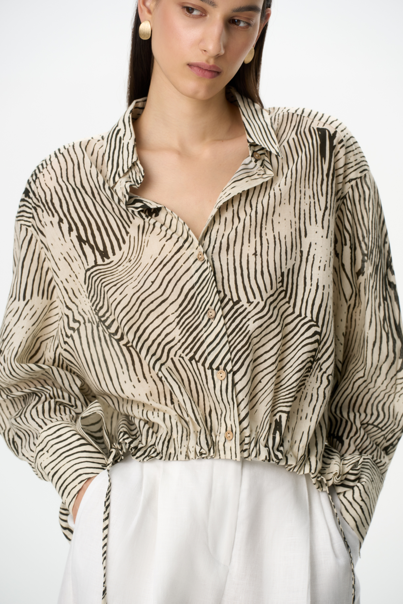 Принтованная рубашка из 100% хлопка. Модель свободного силуэта, с удлиненной спинкой, длинными рукавами, классическим отложным воротником и регулируемой кулиской спереди. 