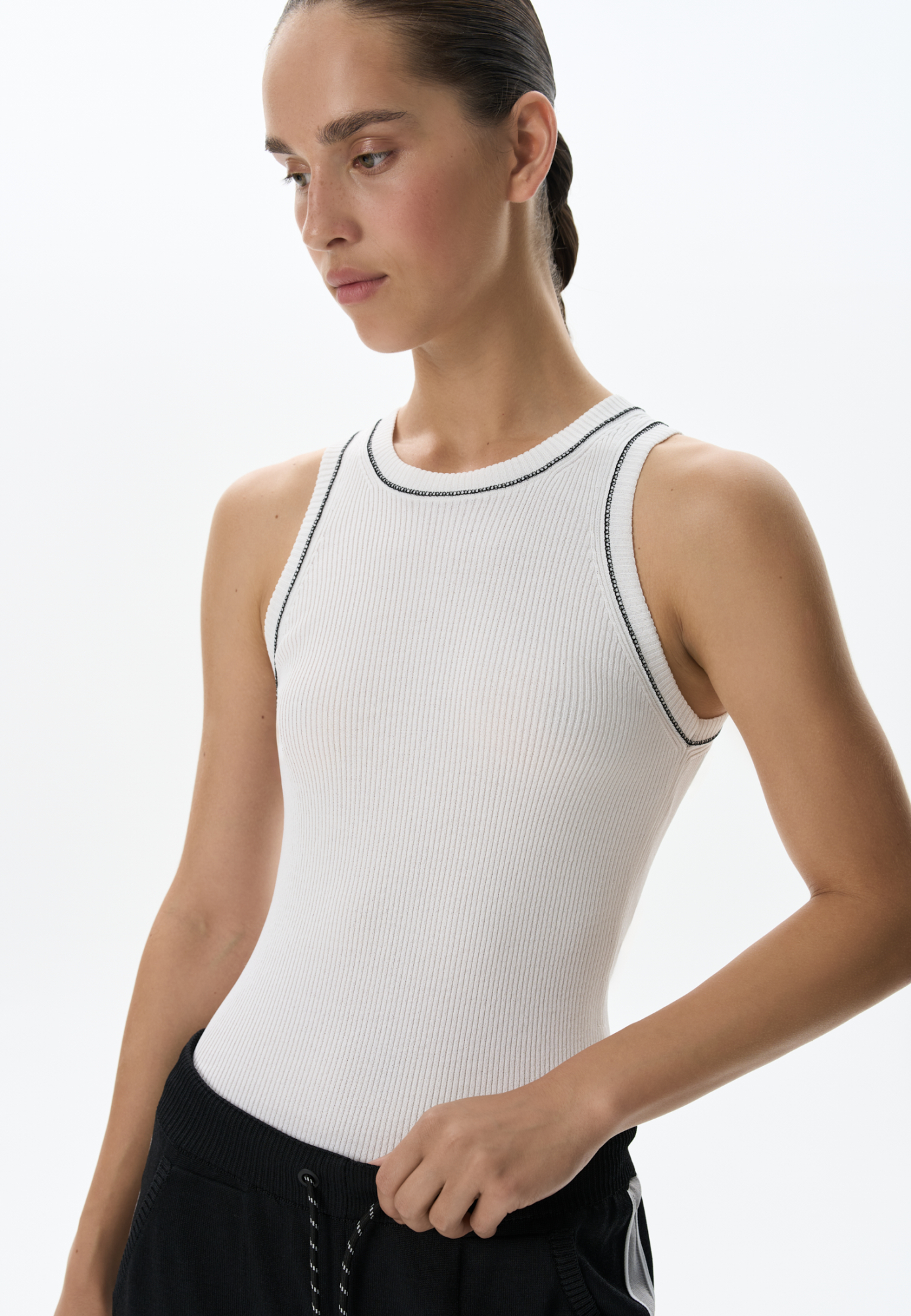 Трикотажный топ из вискозы в рубчик. Модель приталенного силуэта, без рукавов и круглым вырезом горловины. Изделие декорировано строчкой контрастного цвета.